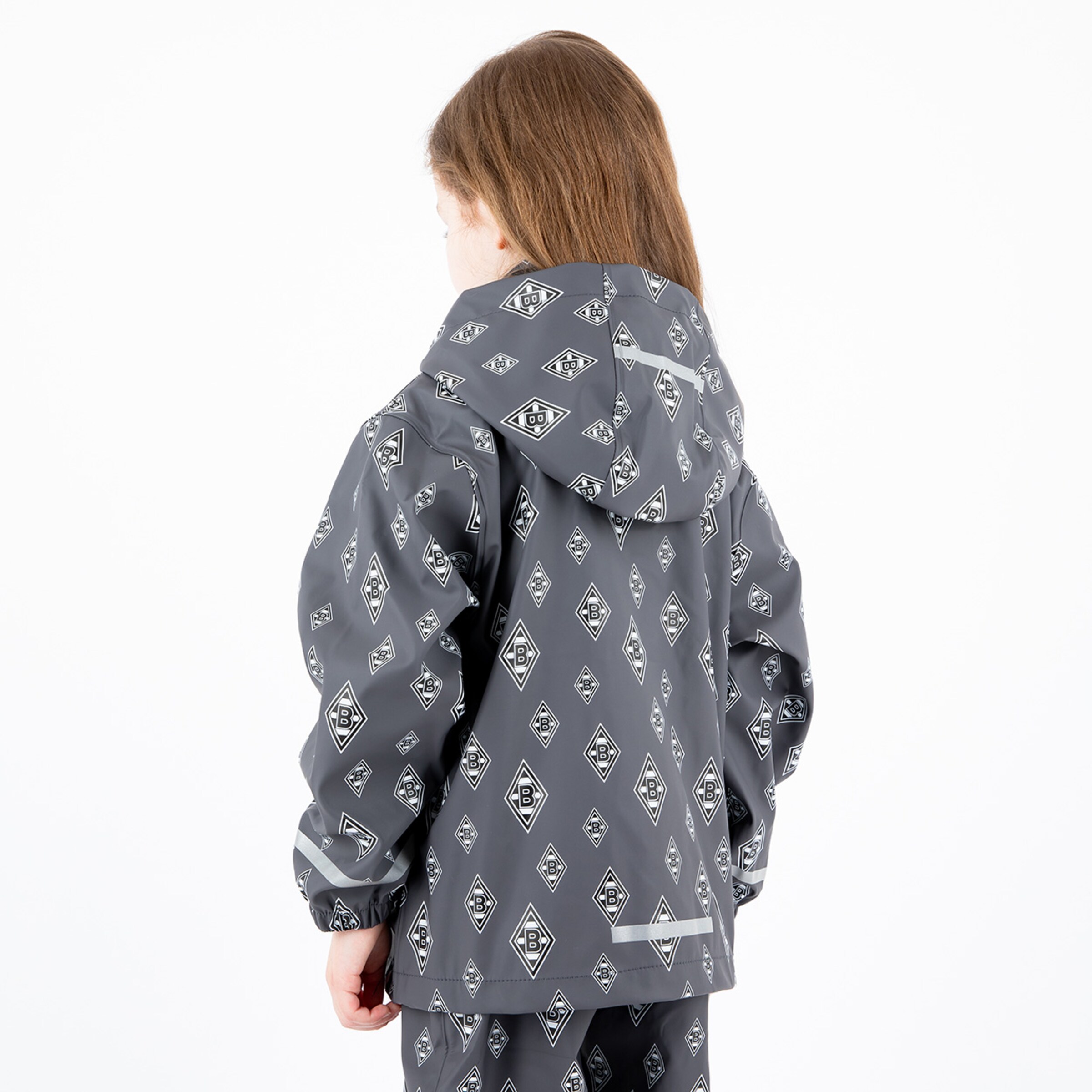 Ein Mädchen trägt eine graue gemusterte Regenjacke und blickt nach hinten.