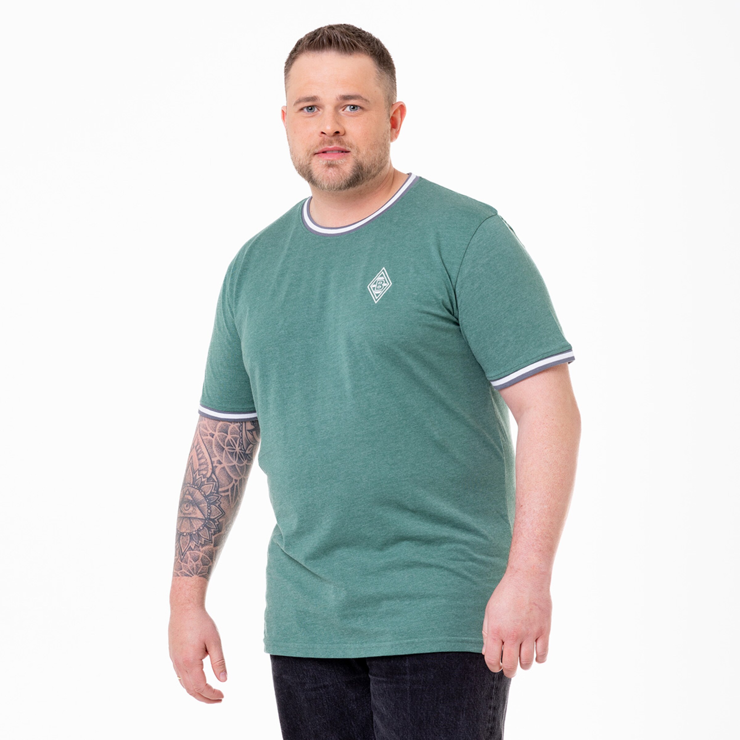 A man with a tattoo is standing in a green striped t-shirt.