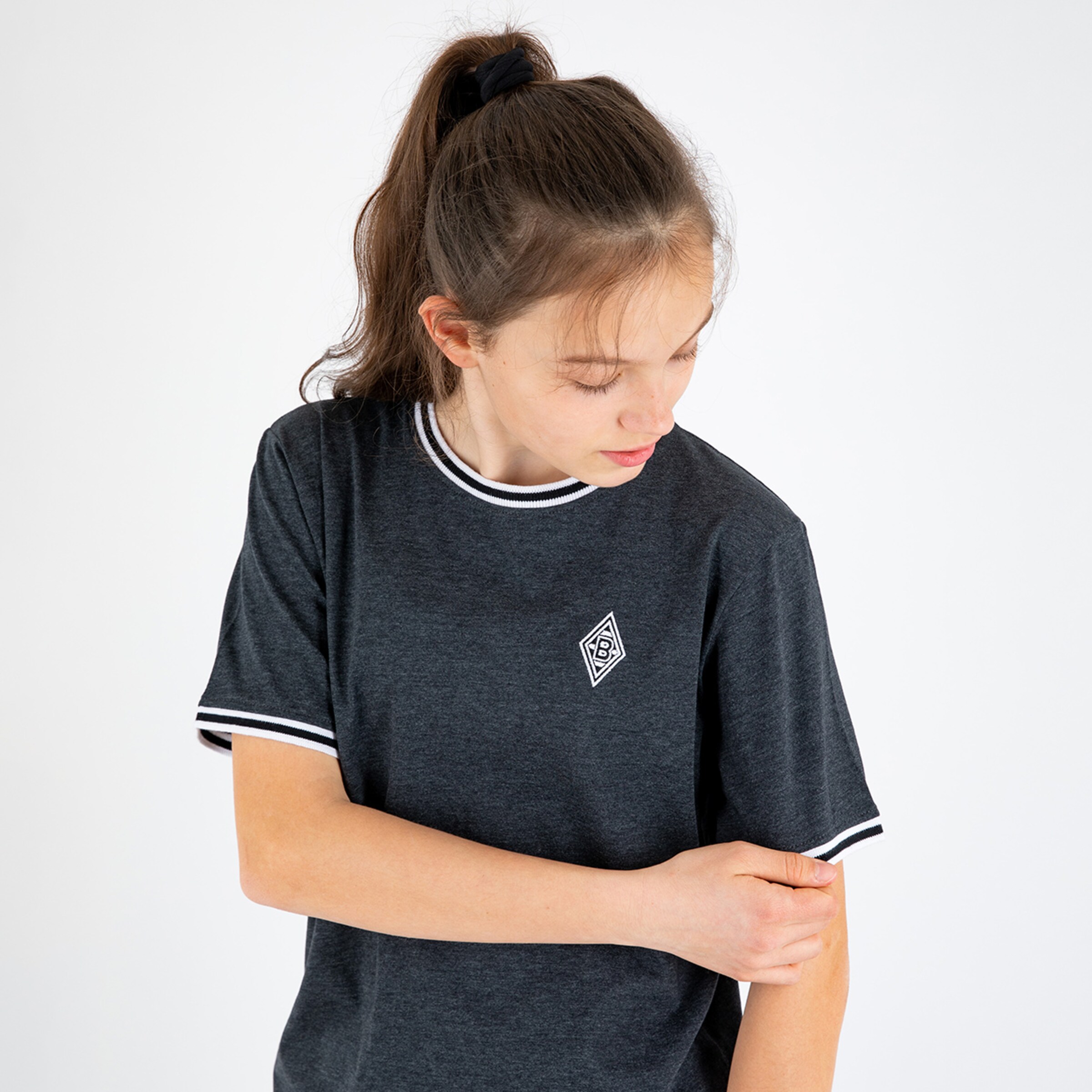 A young woman with long hair wearing a black t-shirt with white trim and a small logo.