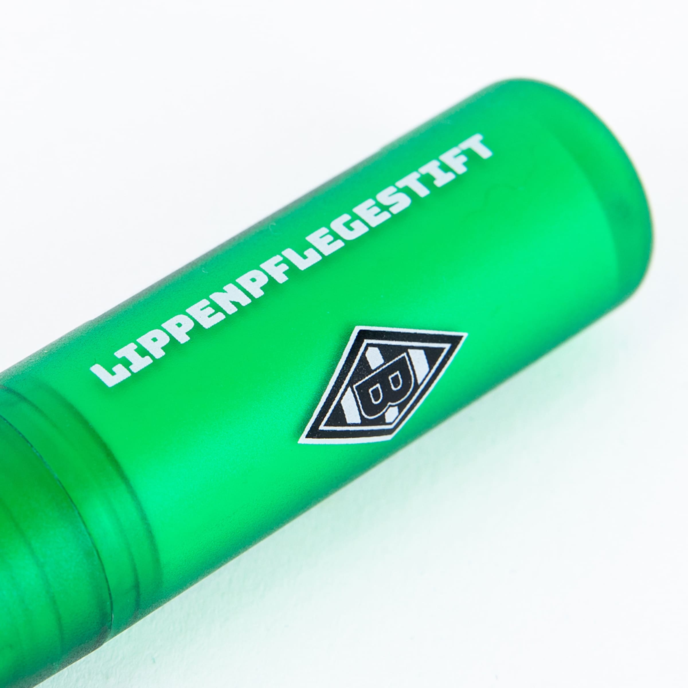 Grüner Lippenpflegestift mit weißem Text „LIPPENPFLEGESTIFT“ und dem Logo von Borussia Mönchengladbach auf weißem Grund.