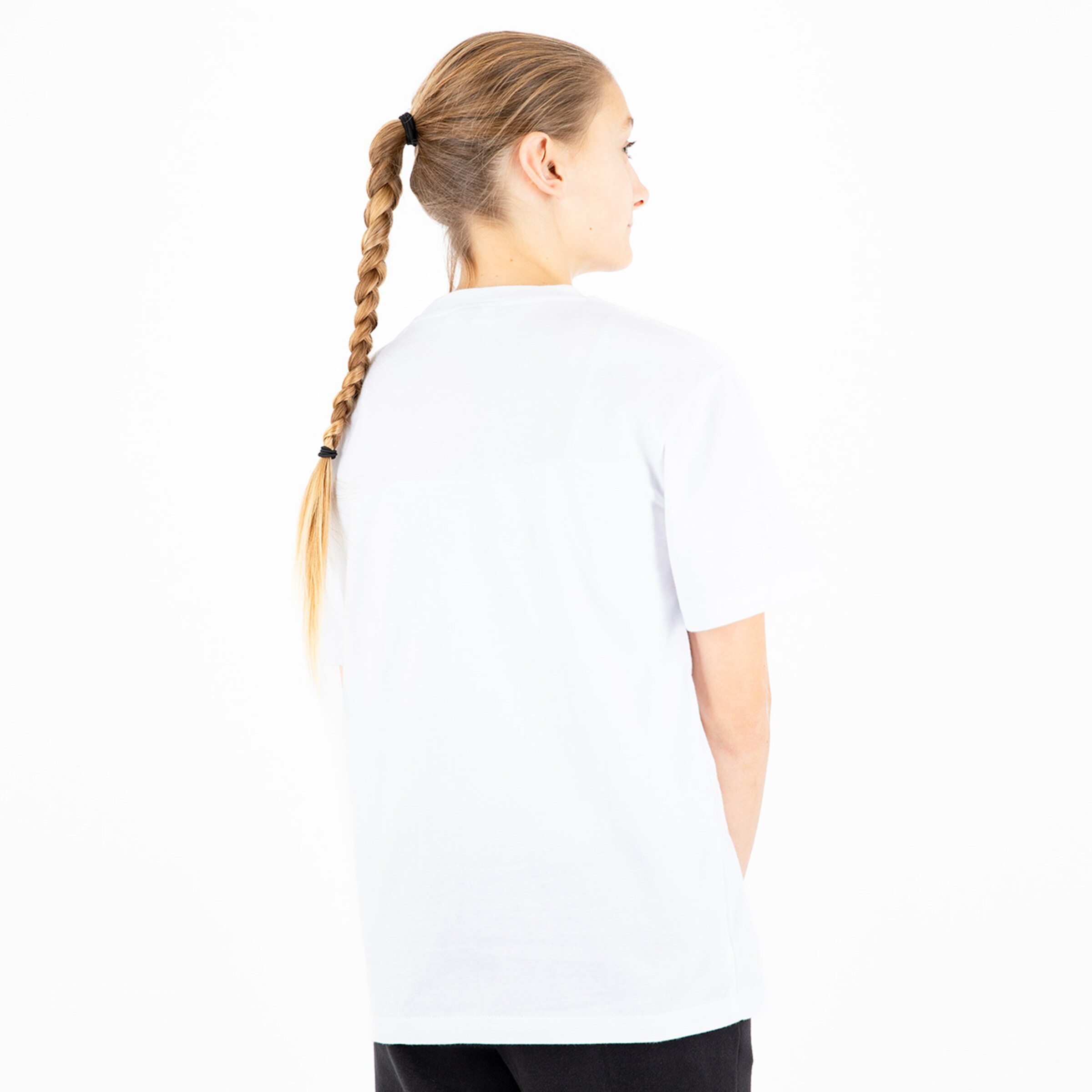 Woman with long braided hair wearing a white T-shirt standing with her back to the camera.