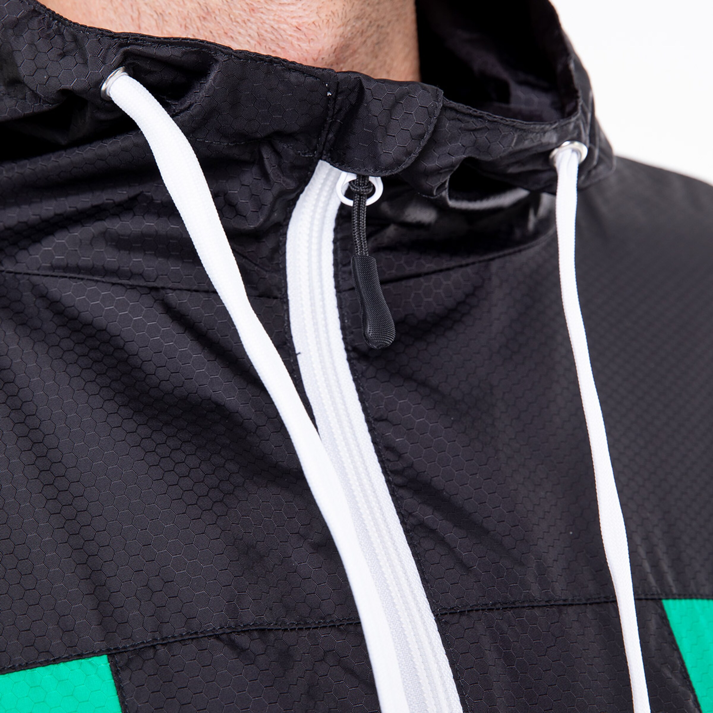 Detailaufnahme eines schwarz-grünen Sportjacke mit Kapuze und Kordelzug.