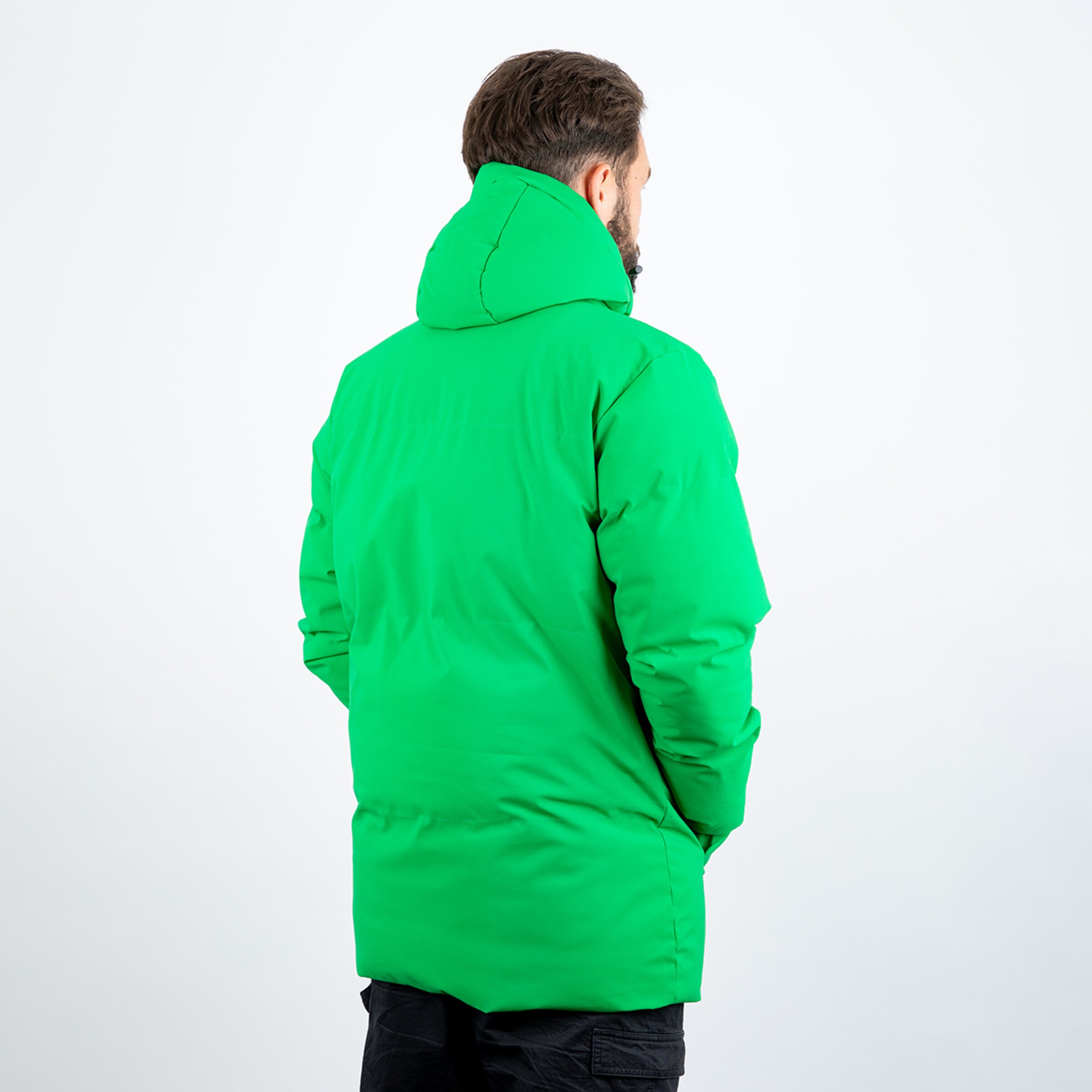 Grüner Parka von hinten mit Kapuze und Händen in den Taschen.