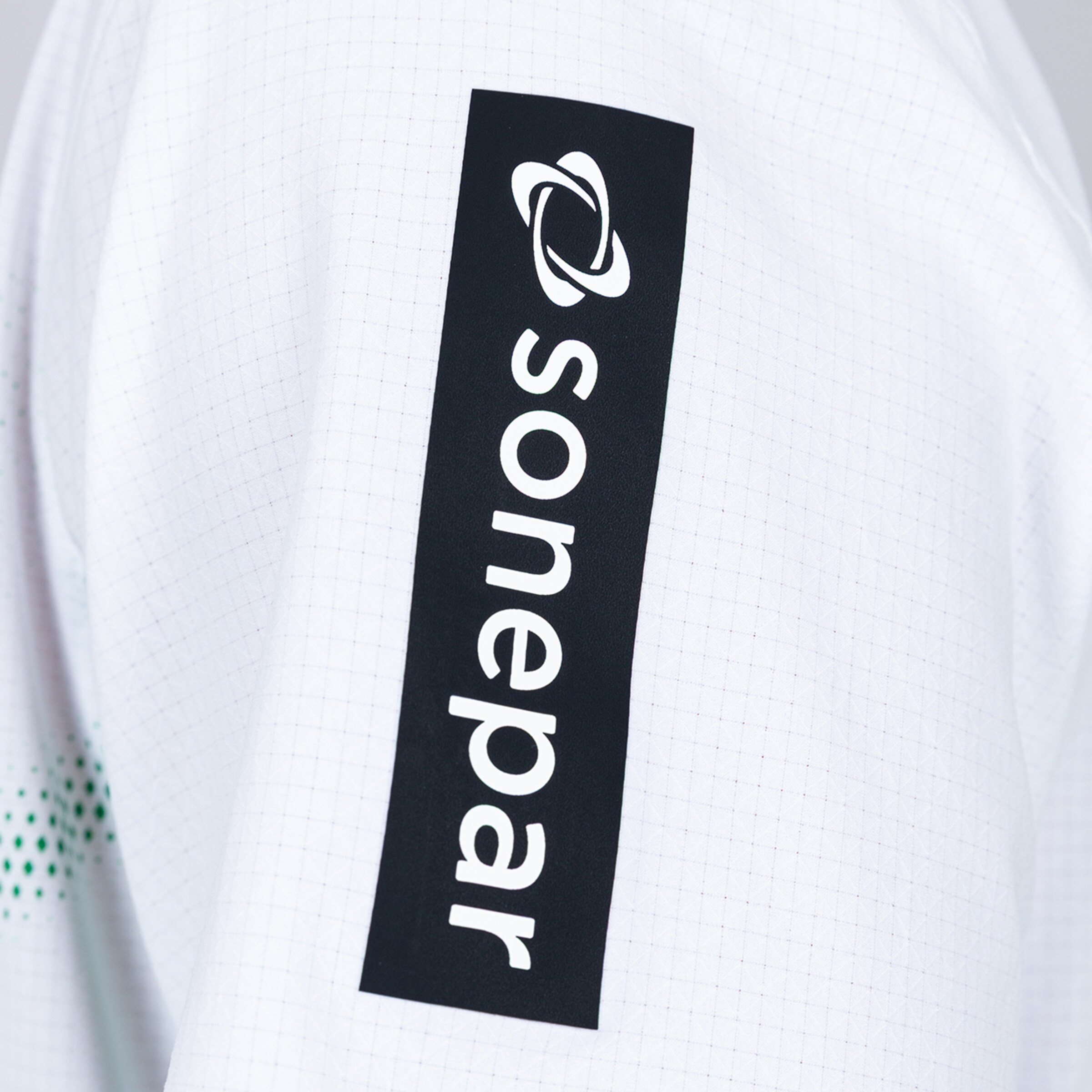 Close-up of white fabric with a vertical black patch featuring the white Sonepar logo and brand icon.