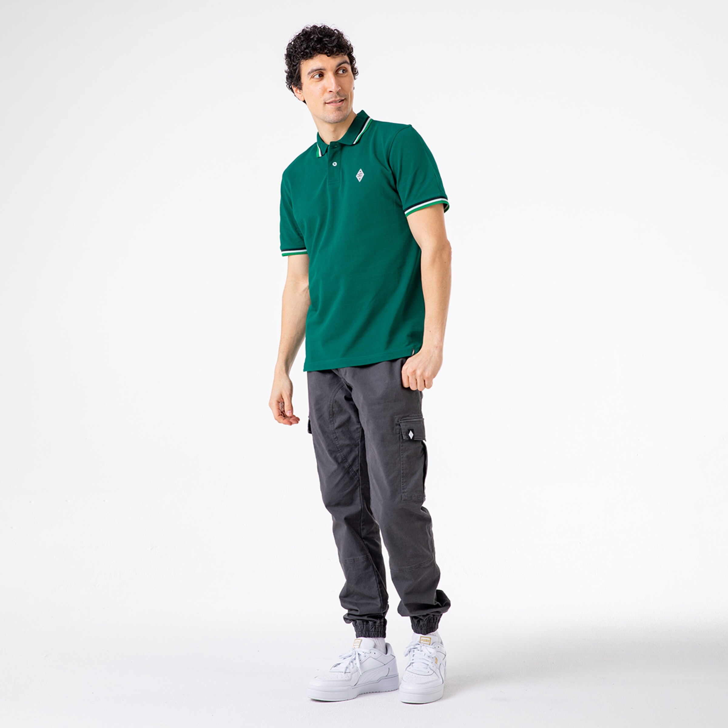 Mann in grünem Polohemd und grauen Cargo-Hosen mit weißen Sneakers