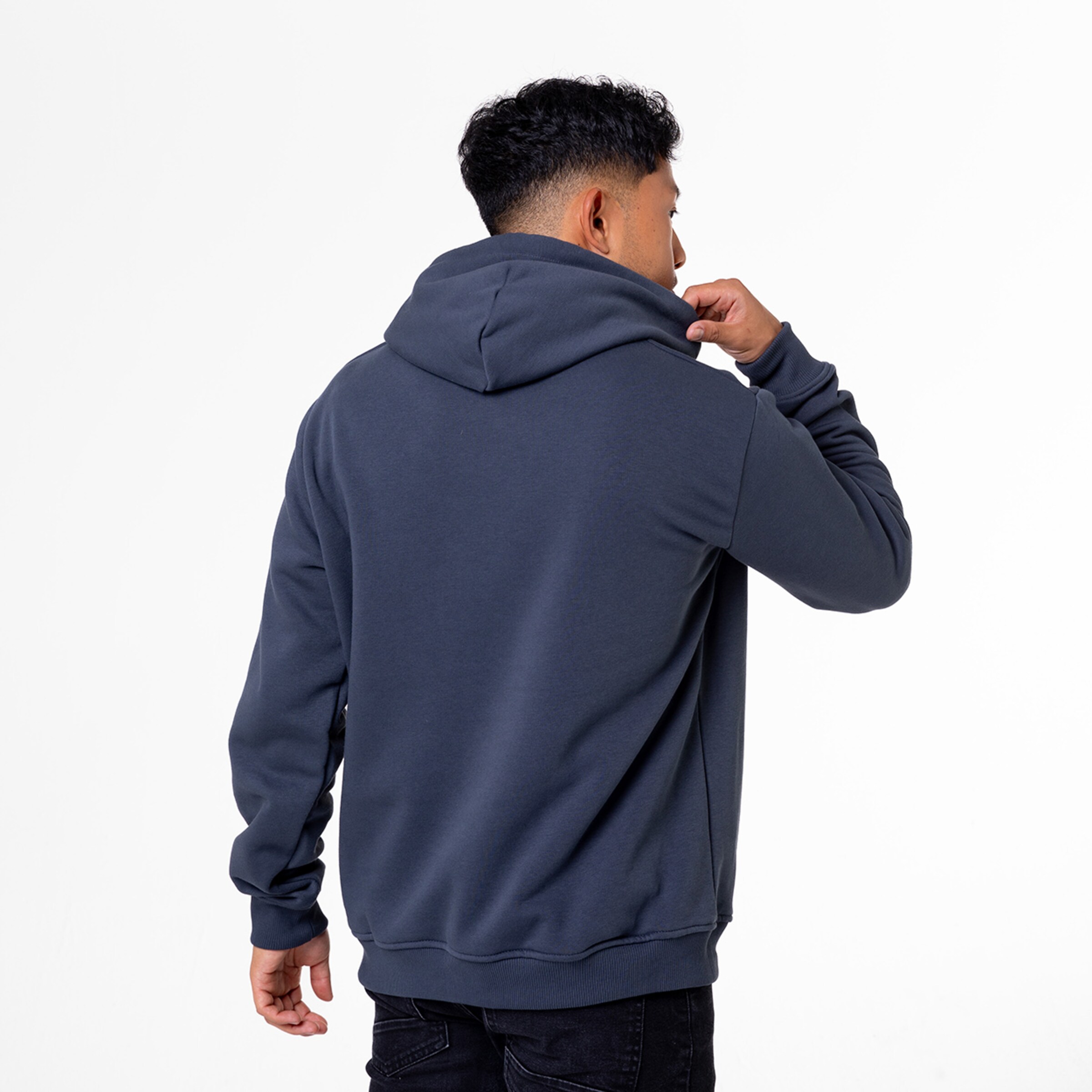 Mann trägt einen grauen Kapuzenpullover schaut über die Schulter zurück.