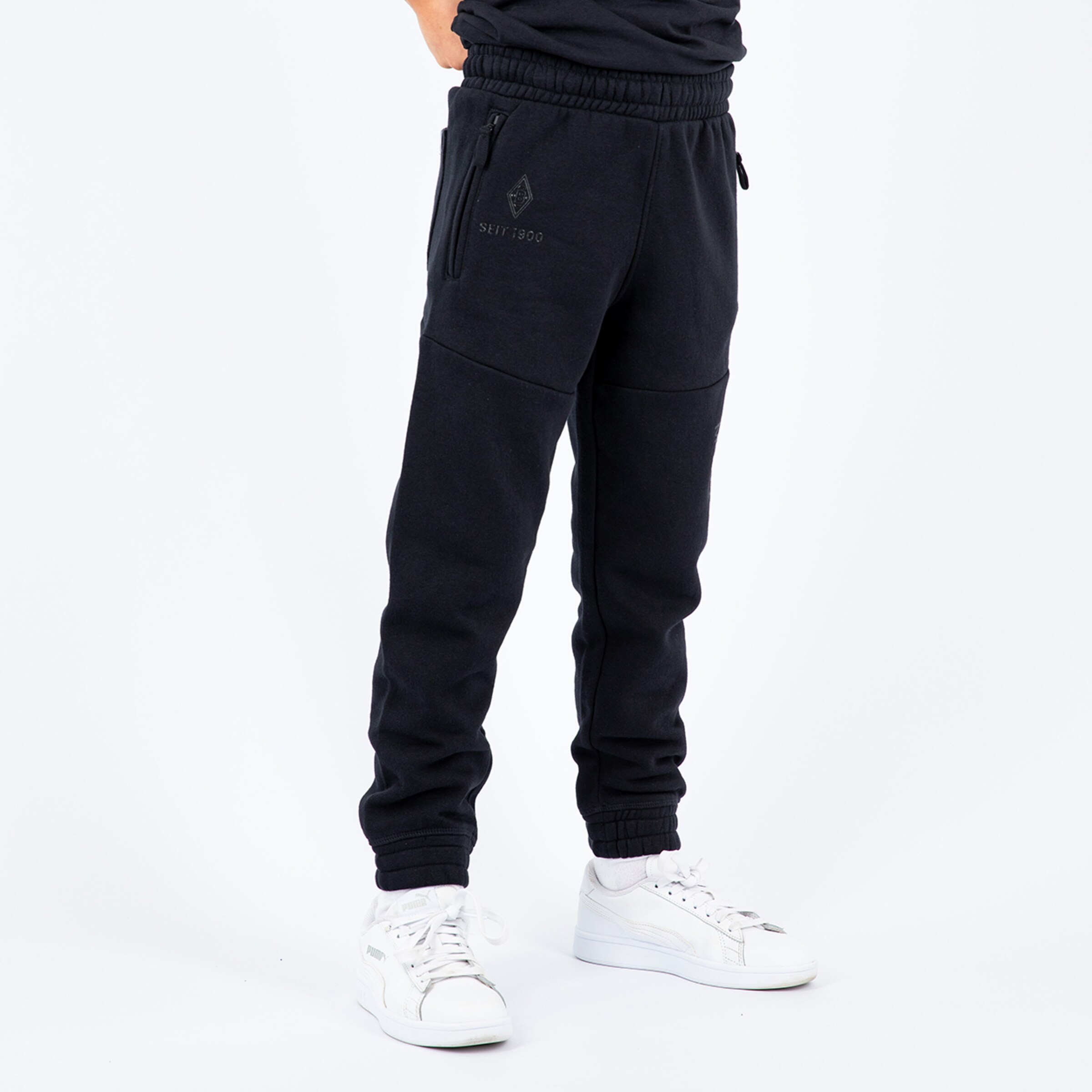 Schwarze Jogginghose mit Taschen und elastischem Hüftbund kombiniert mit weißen Sneakers.