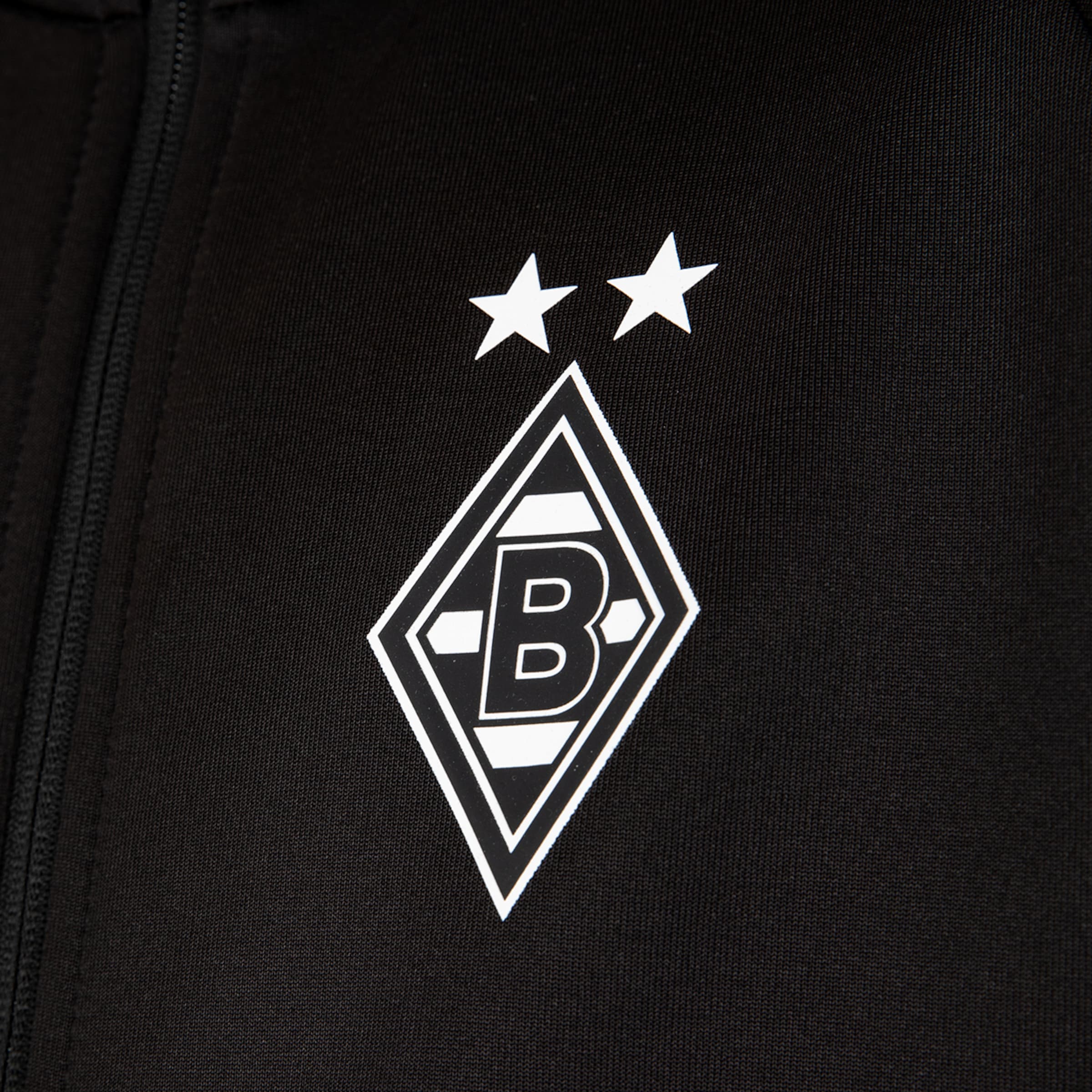 Logo von Borussia Mönchengladbach auf schwarzem Stoff: Weiße Raute mit einem schwarzen „B“ und zwei weißen Sternen darüber.