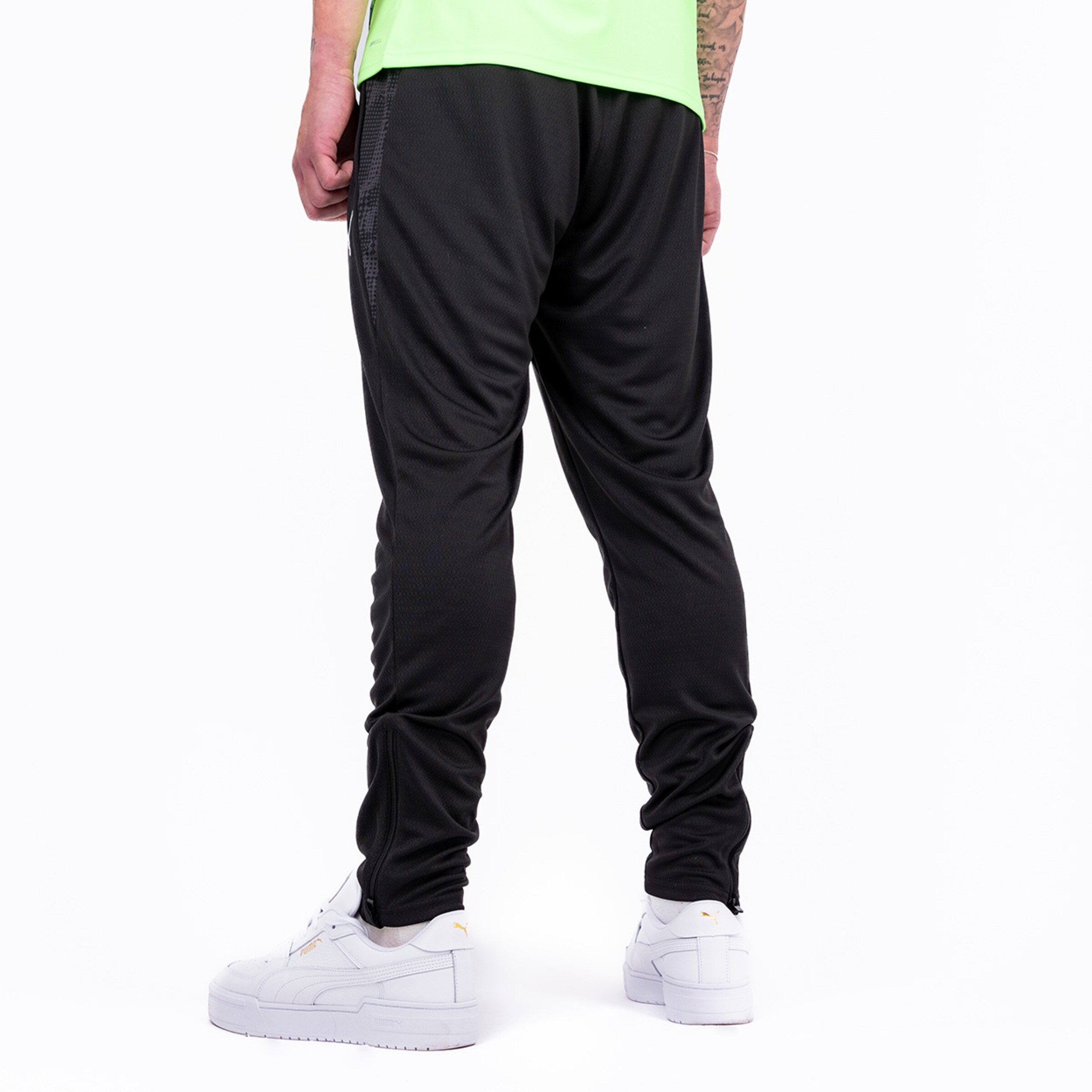 Hinteransicht einer Person in schwarzen Jogginghosen und weißen Sneakers.