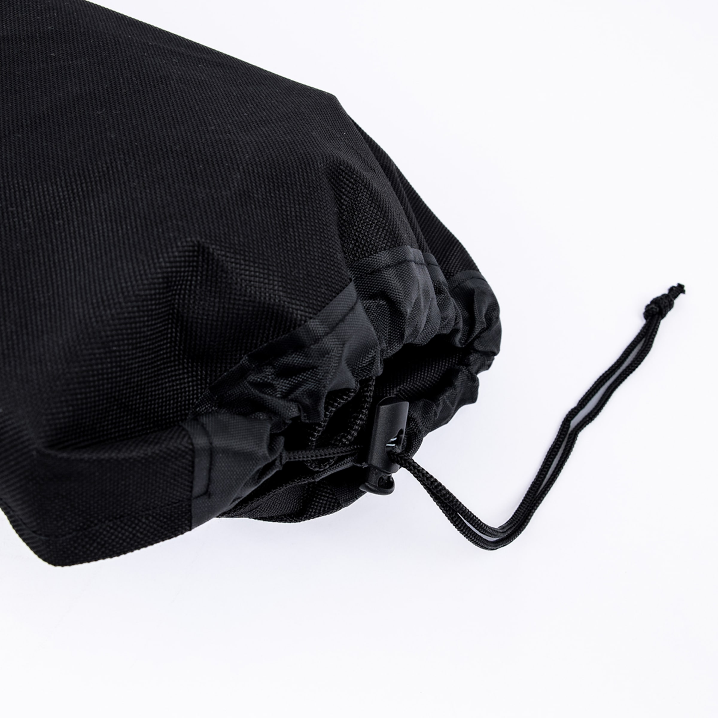 Detailansicht eines schwarzen Stoffbeutels mit Kordelzug, schwarzem Stopper und Knoten vor weißem Hintergrund.