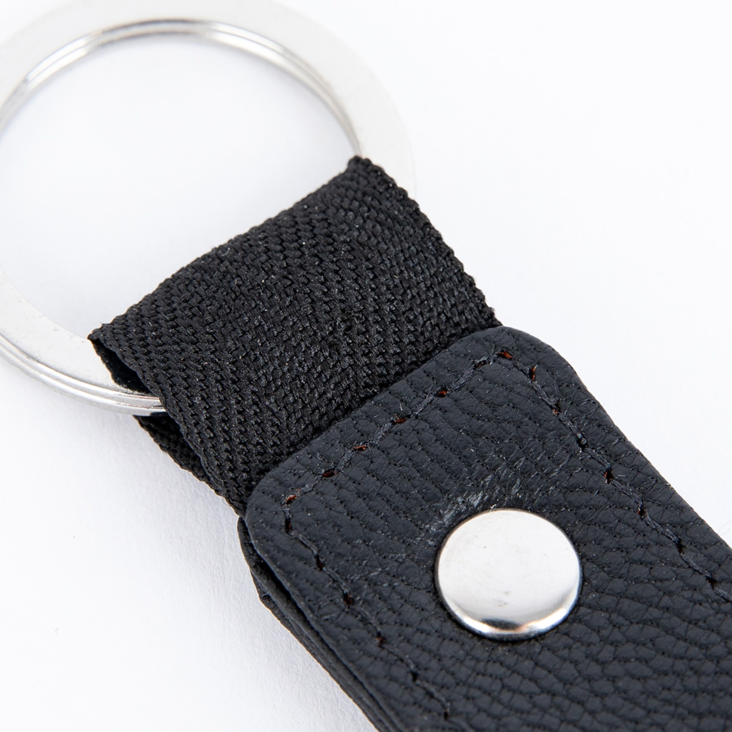 Schlüsselanhänger aus schwarzem Material mit silbernem Schlüsselring.