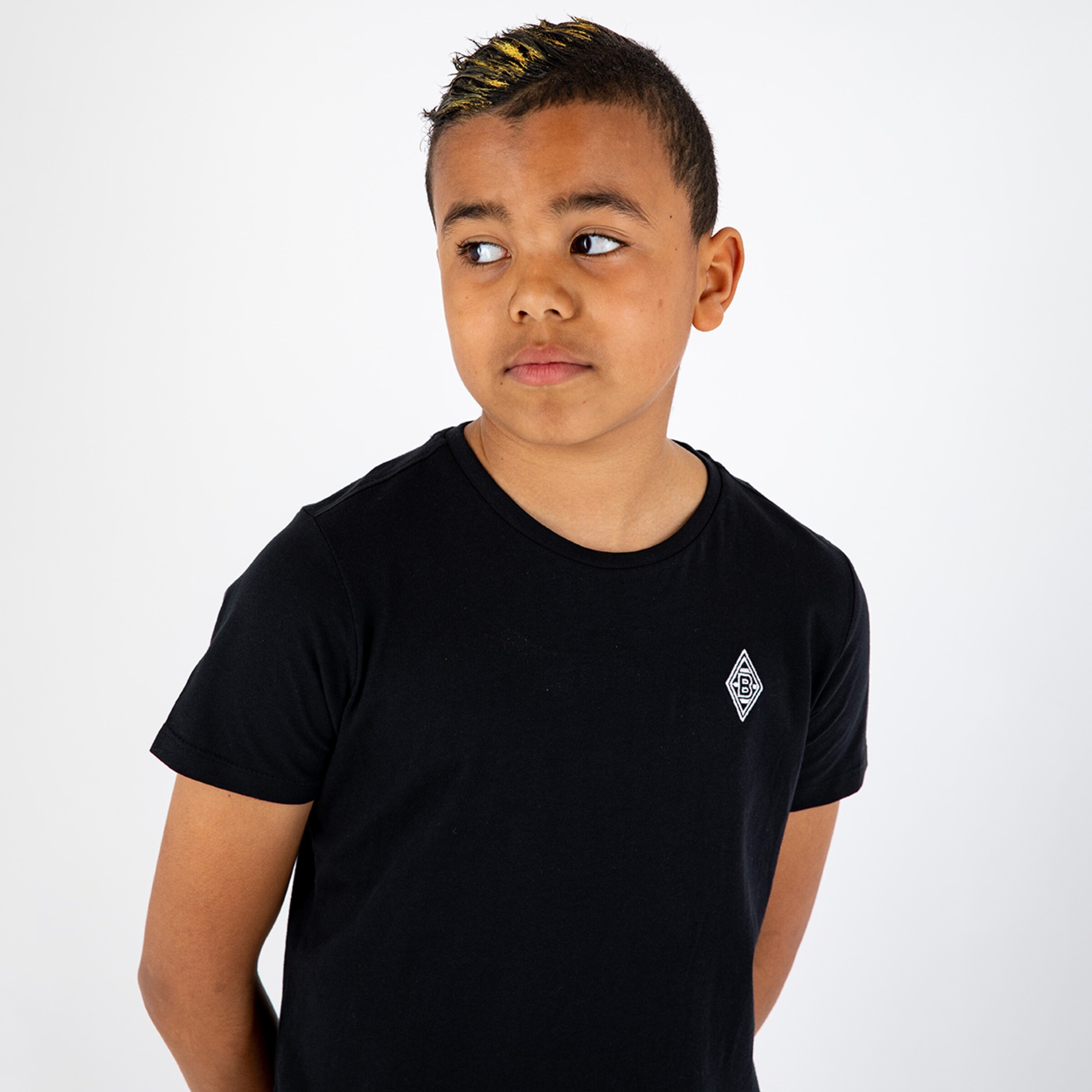 Junger Junge steht in einem schwarzen T-Shirt mit Borussia Mönchengladbach-Logo schaut nachdenklich zur Seite.