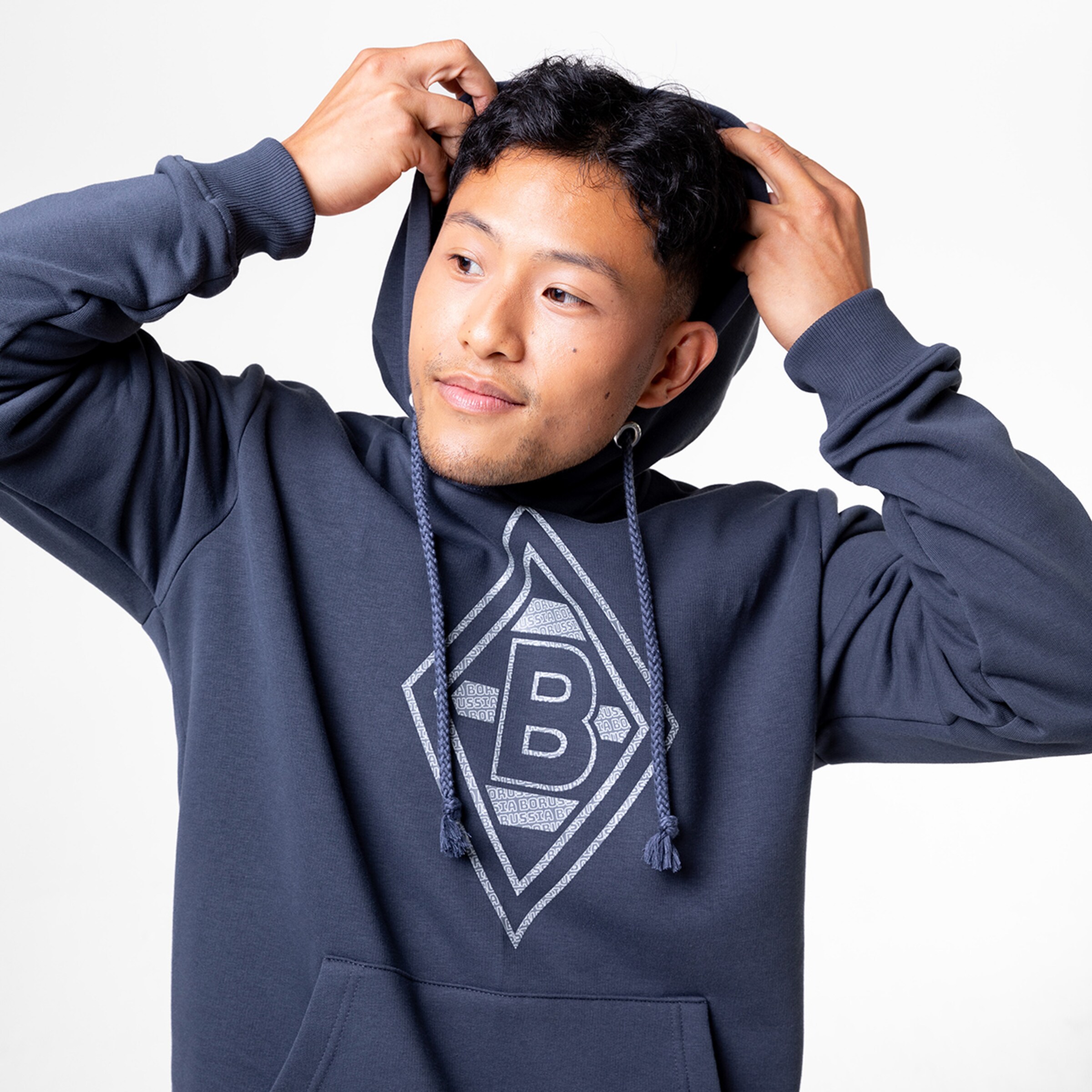 Junger Mann trägt einen grauen Hoodie mit dem Borussia Mönchengladbach Logo.
