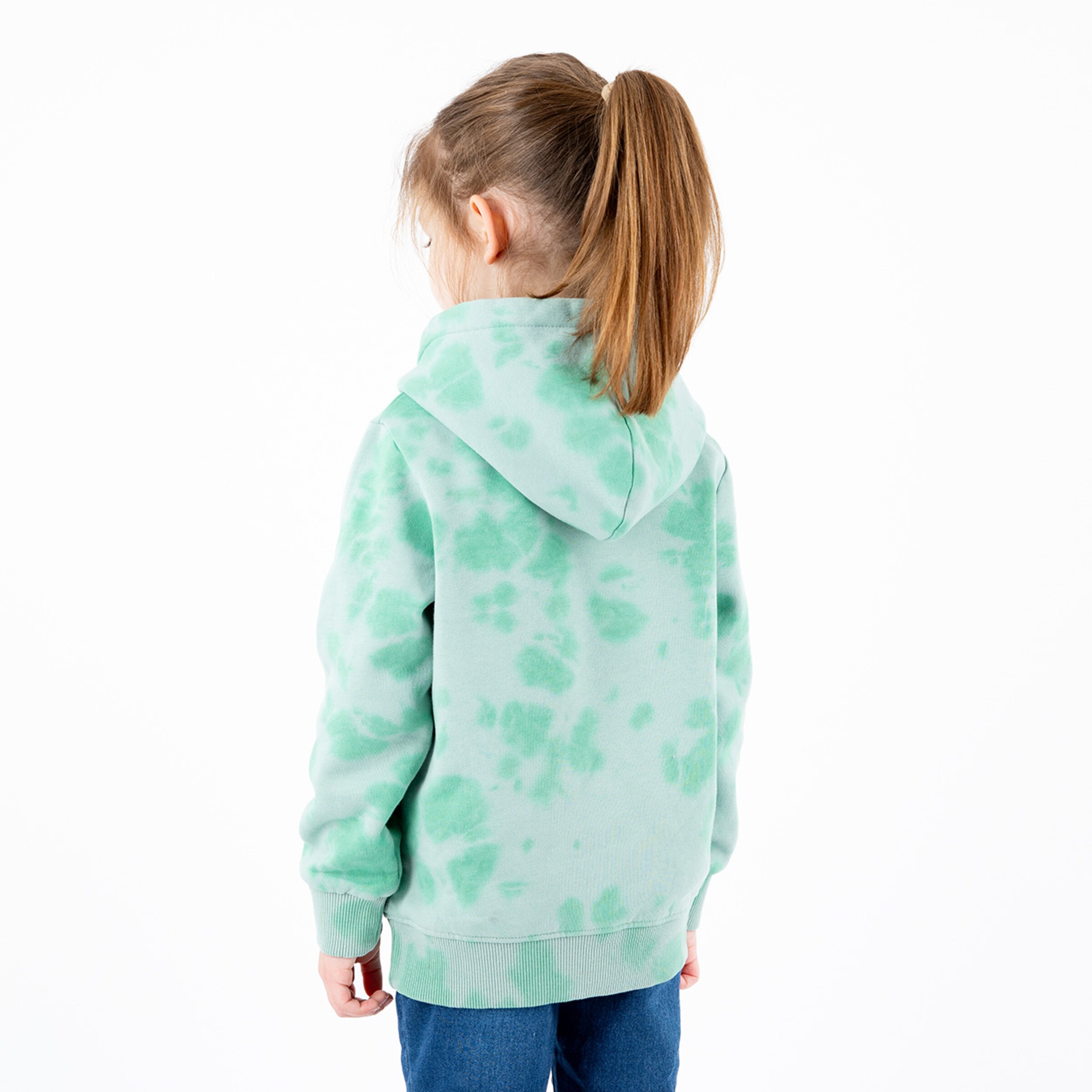 A girl wearing a mint green tie-dye hoodie stands with her back to the camera.