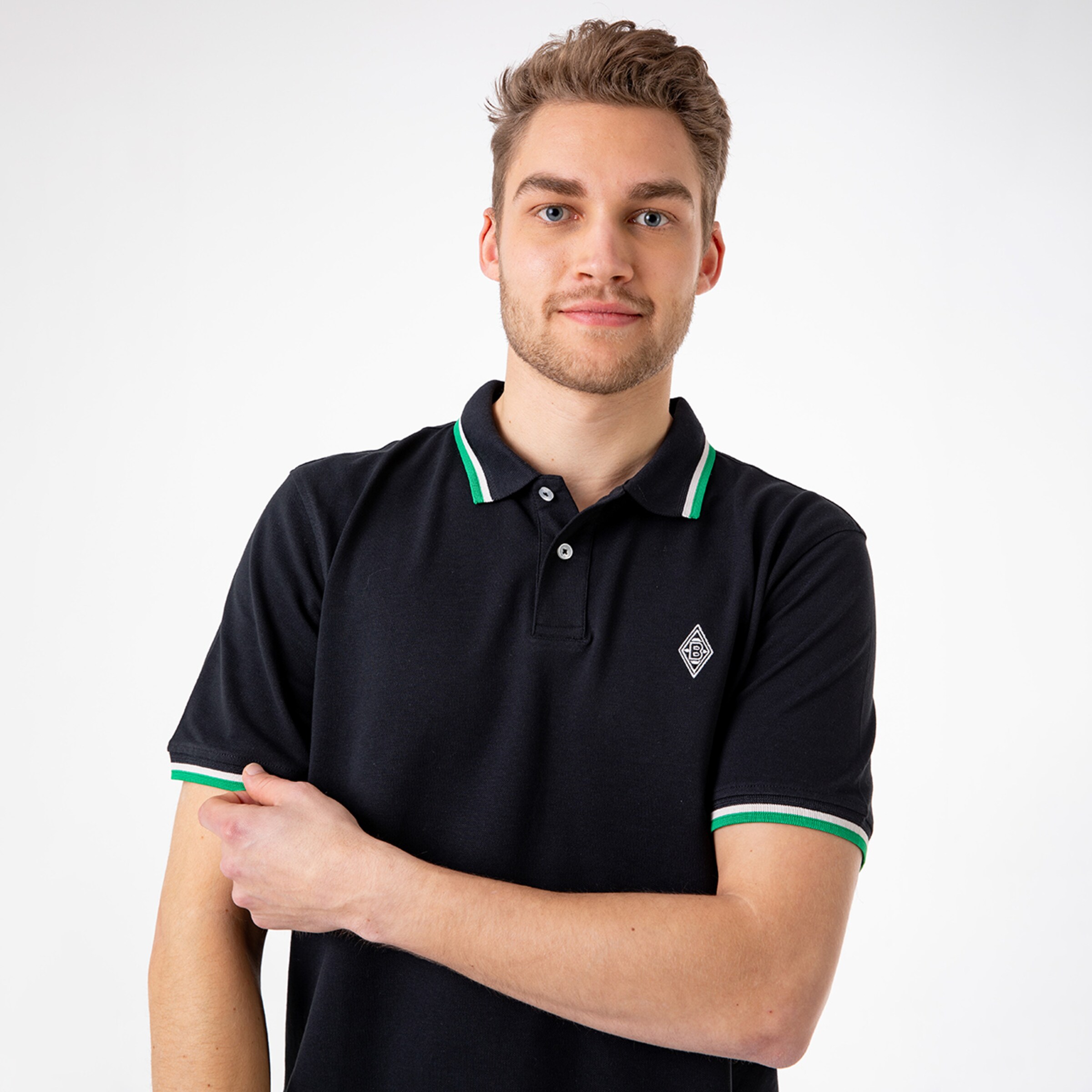 Man wearing a black polo shirt with green and white accents and a logo on the chest.