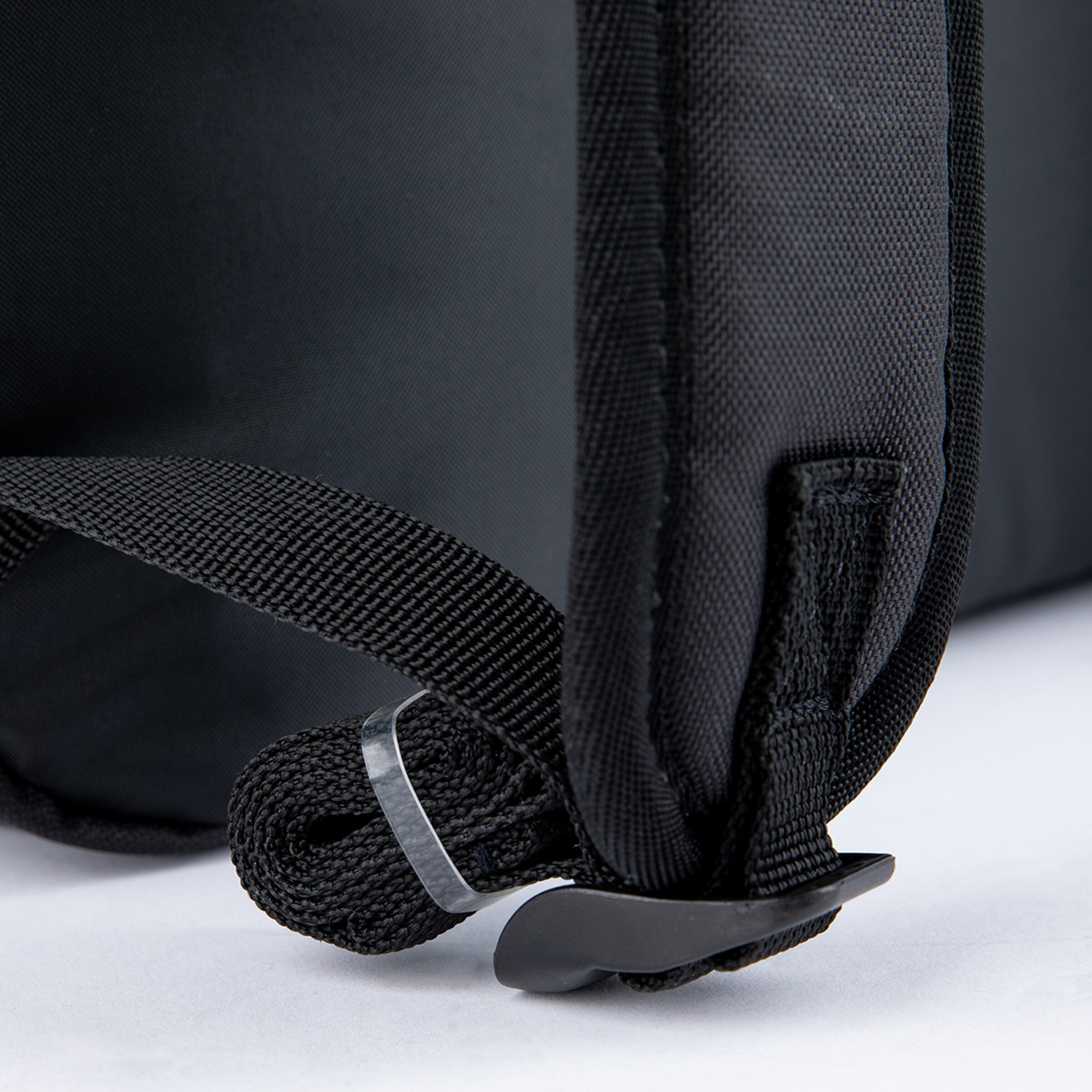 Detailaufnahme einer schwarzen Tasche mit textilem Tragegurt und Kunststoffverschluss.