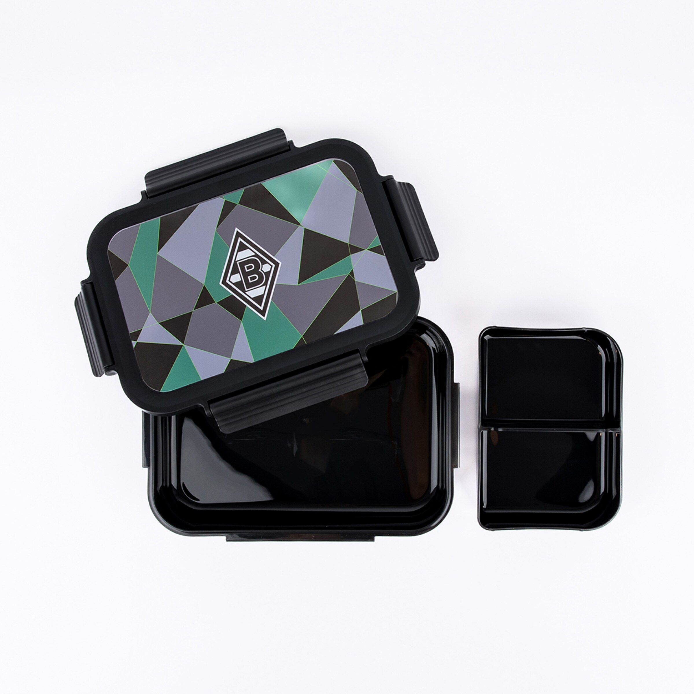 Open black lunch box with a geometric green, grey, and black patterned lid featuring the Borussia Mönchengladbach logo. A separate black two-compartment container is beside it on a white background.