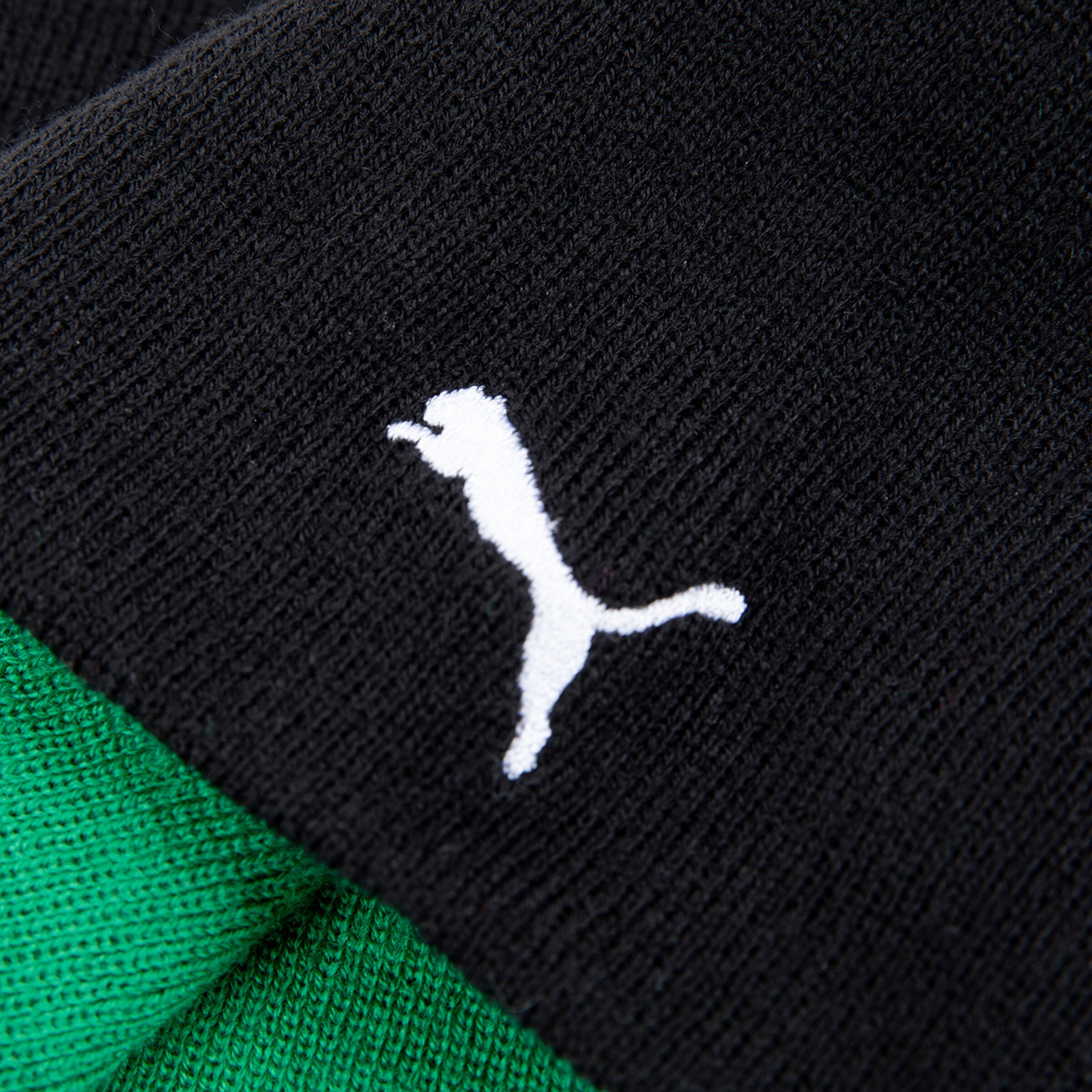 Nahaufnahme eines schwarzen Strickmusters mit Puma-Logo.