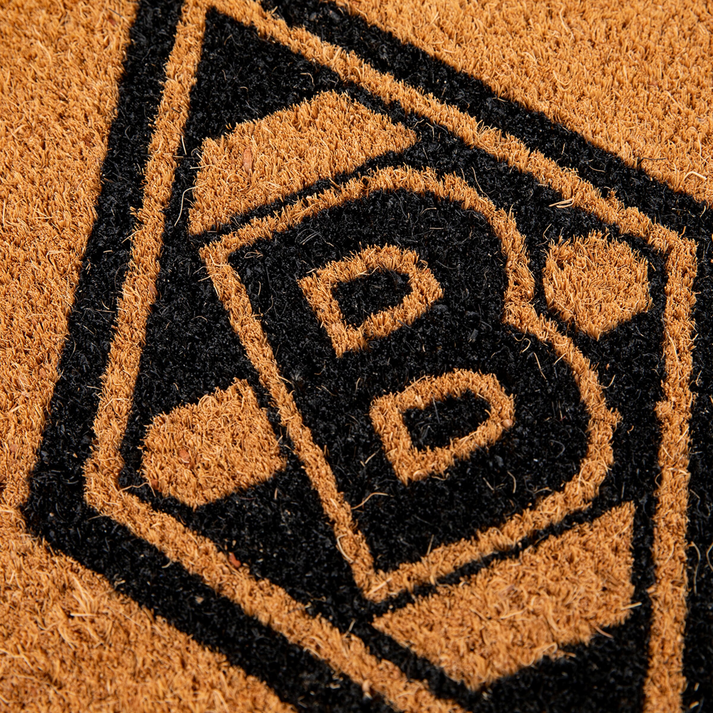 Detailansicht einer Kokosmatte mit dem schwarz-braunen Logo des Fußballvereins Borussia Mönchengladbach.