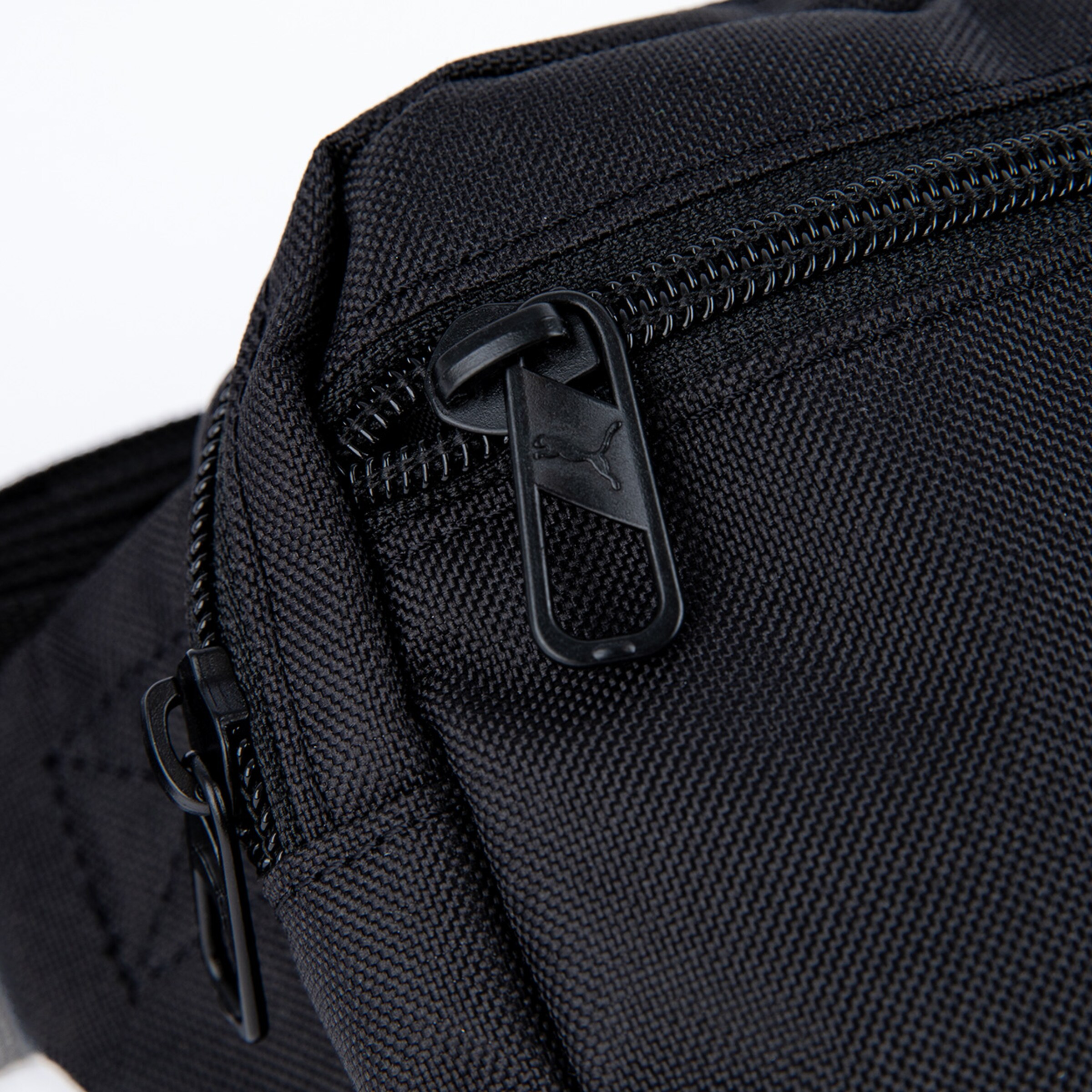 Detailaufnahme eines schwarzen Puma-Reißverschlusses an einer Sporttasche.