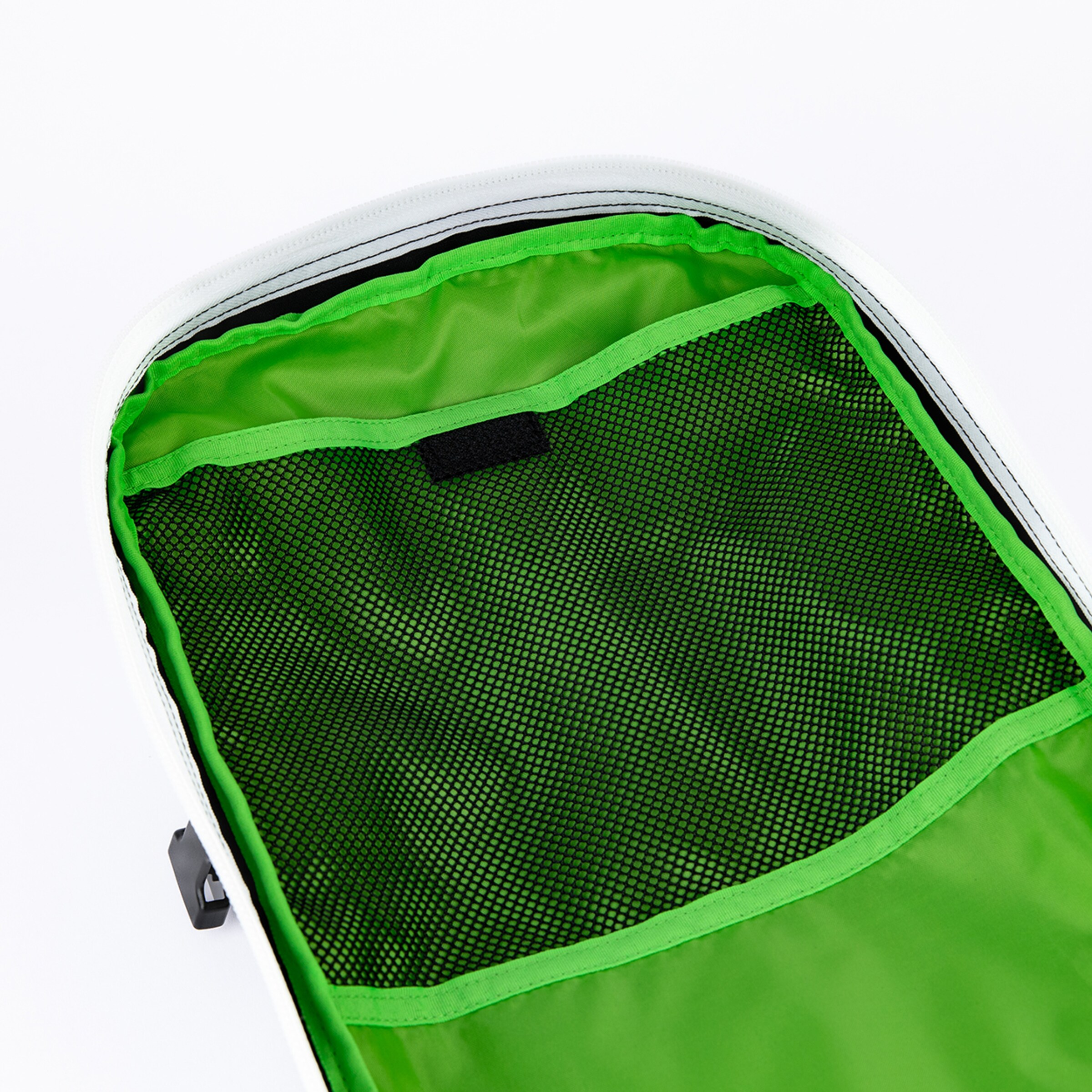 The interior of a white bag reveals a vibrant green lining with a large black mesh pocket. A small black velcro patch is visible above the mesh, highlighting functional organization.