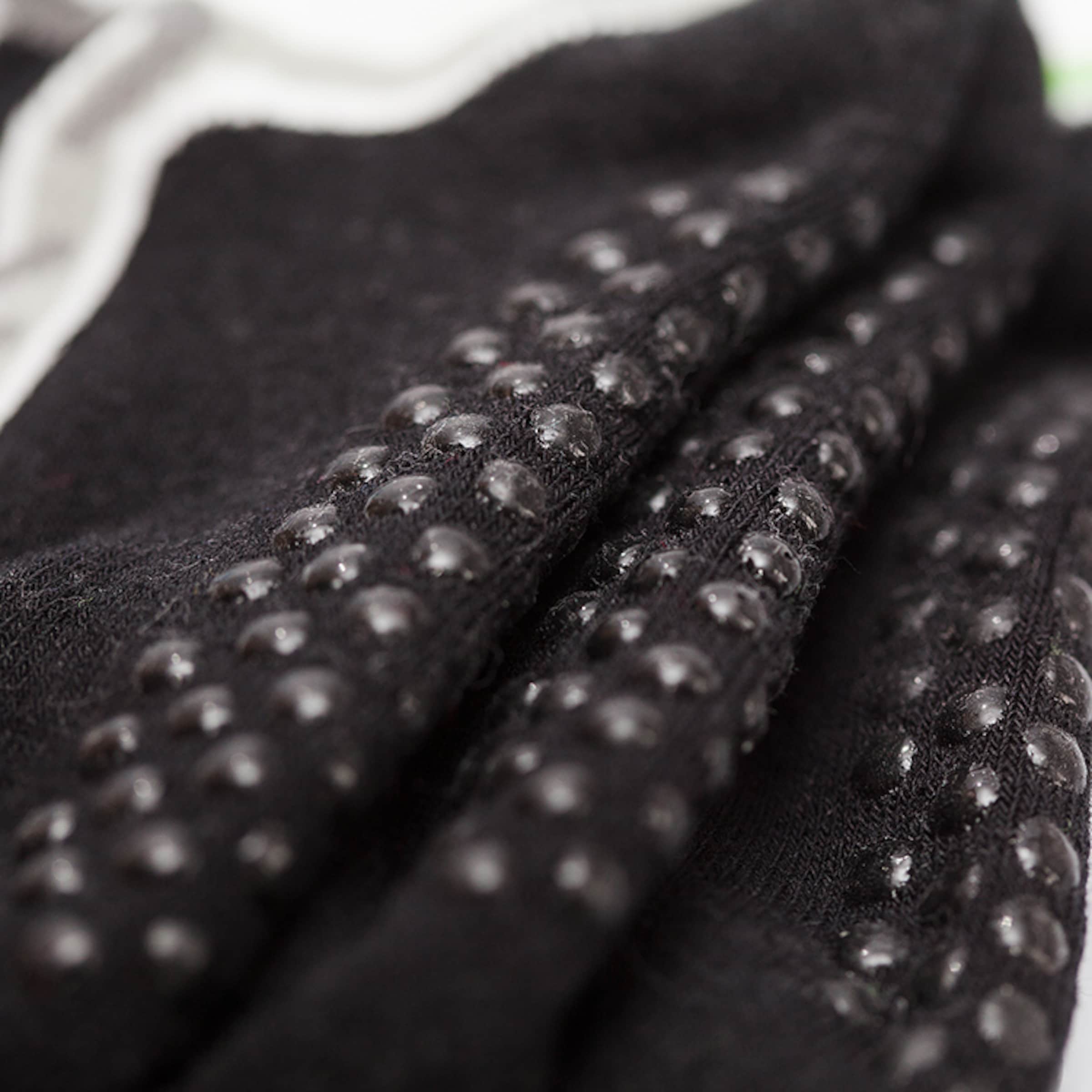 Nahaufnahme von schwarzen Socken mit kleinen, rutschfesten Silikon-Noppen auf der Sohle.