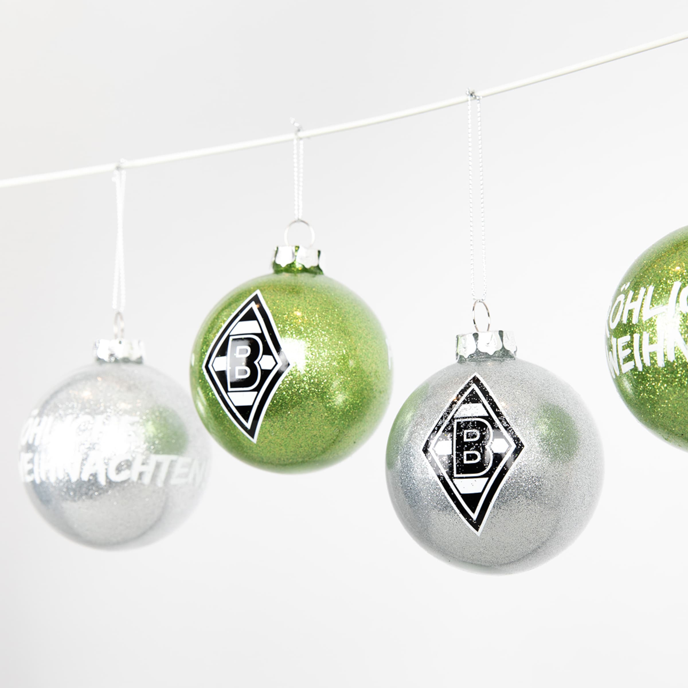Vier glitzernde Borussia Mönchengladbach Weihnachtskugeln in Grün und Silber mit Vereinslogo und Schriftzug „Fröhliche Weihnachten“.