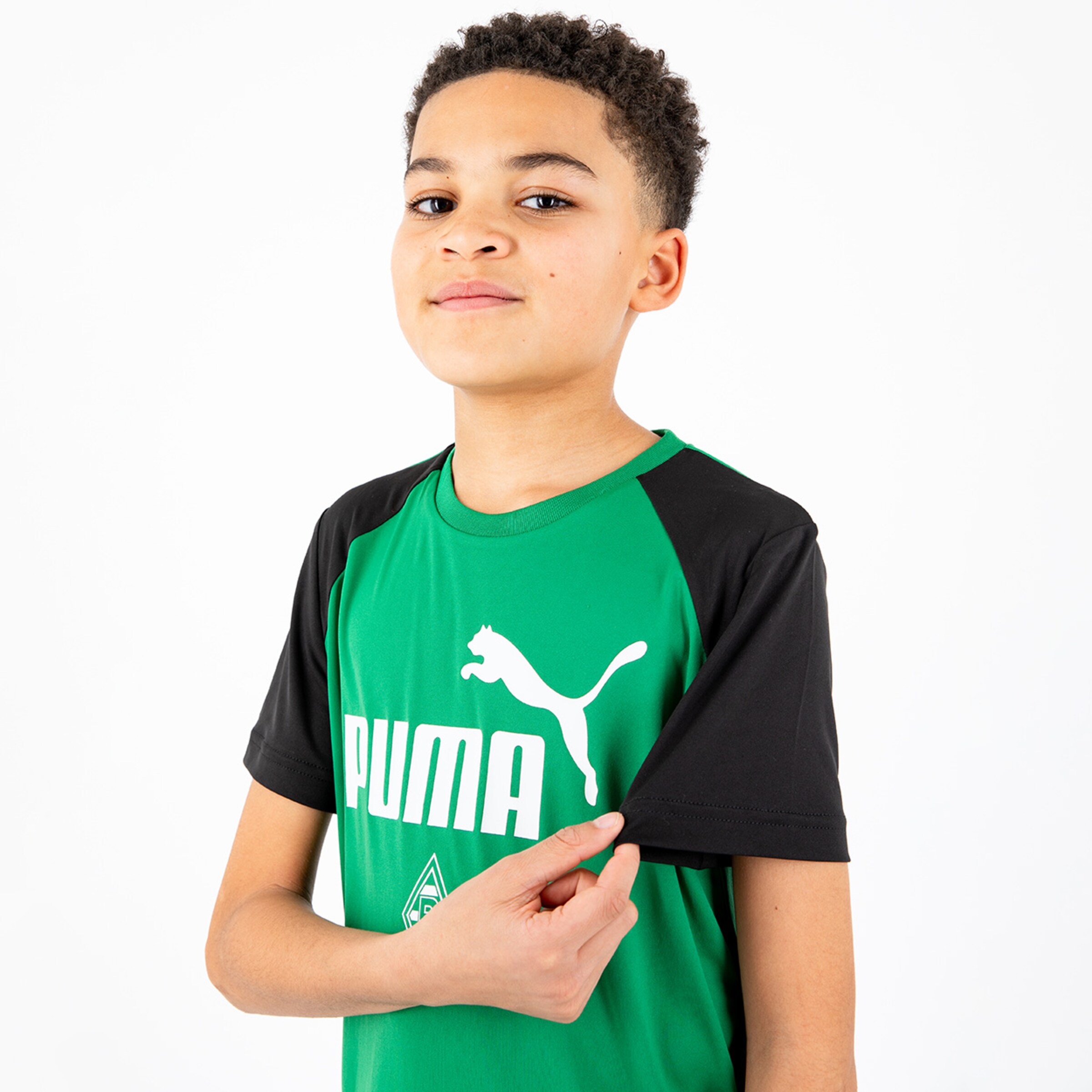 Junge trägt ein grünes Trikot mit schwarzem Ärmel und Puma-Logo er zeigt auf den Ärmel.