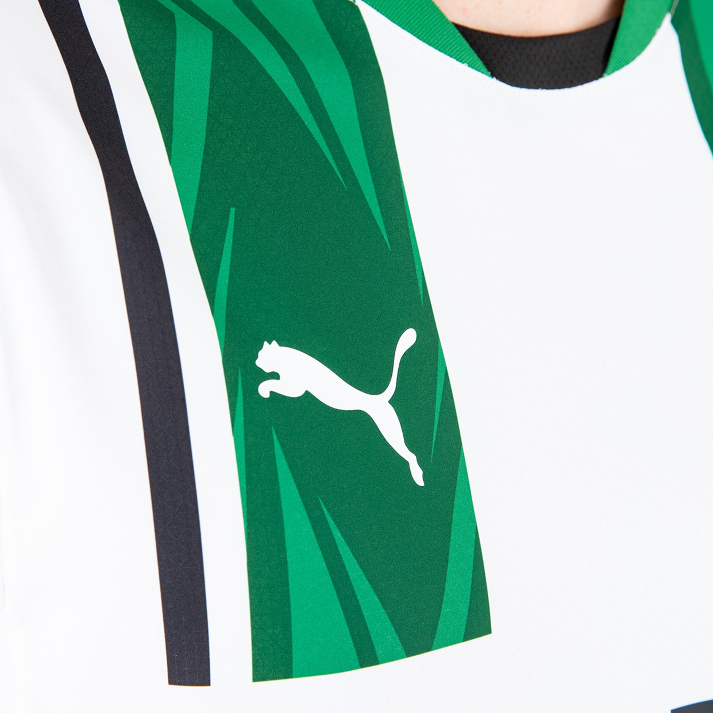 Logo von Puma auf einem Trikot mit grünem Muster.