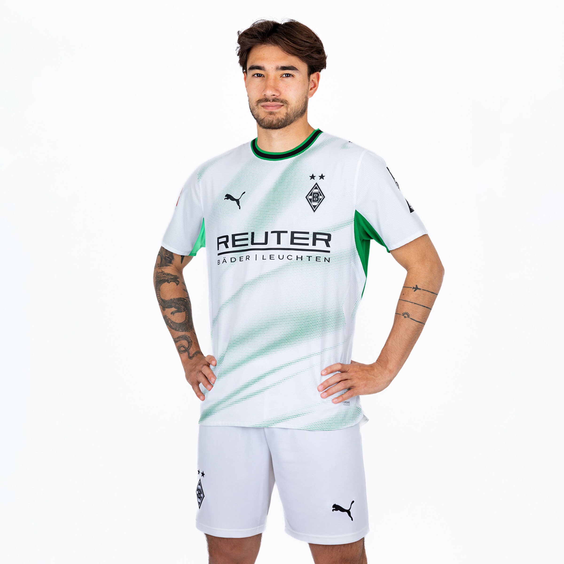 Borussia Mönchengladbach player in a white and green kit posing with hands on hips against a white background.