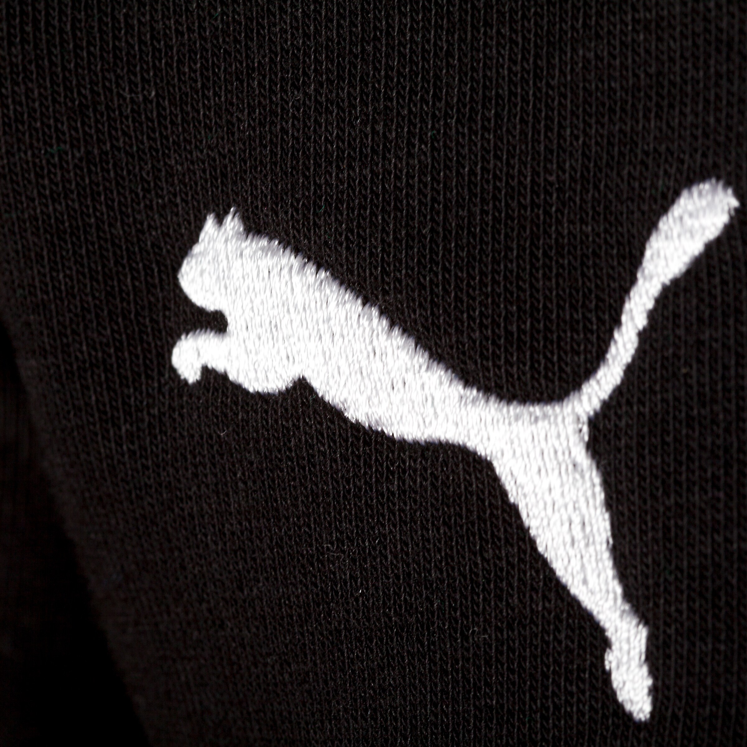Puma logo in white displayed on black fabric.