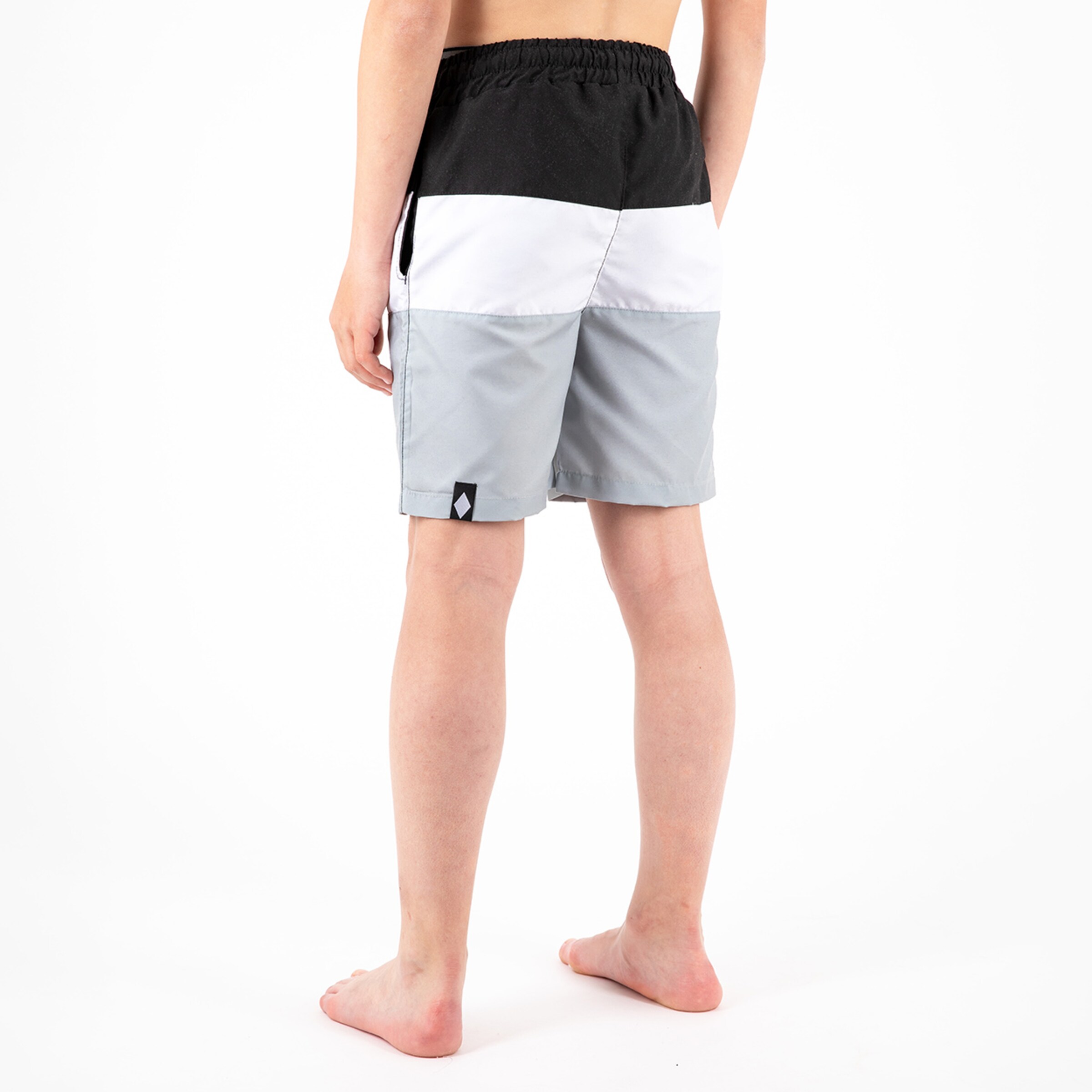 Hinteransicht eines Jungen in Badehosen mit grauen weißen und schwarzen Farbbalken.