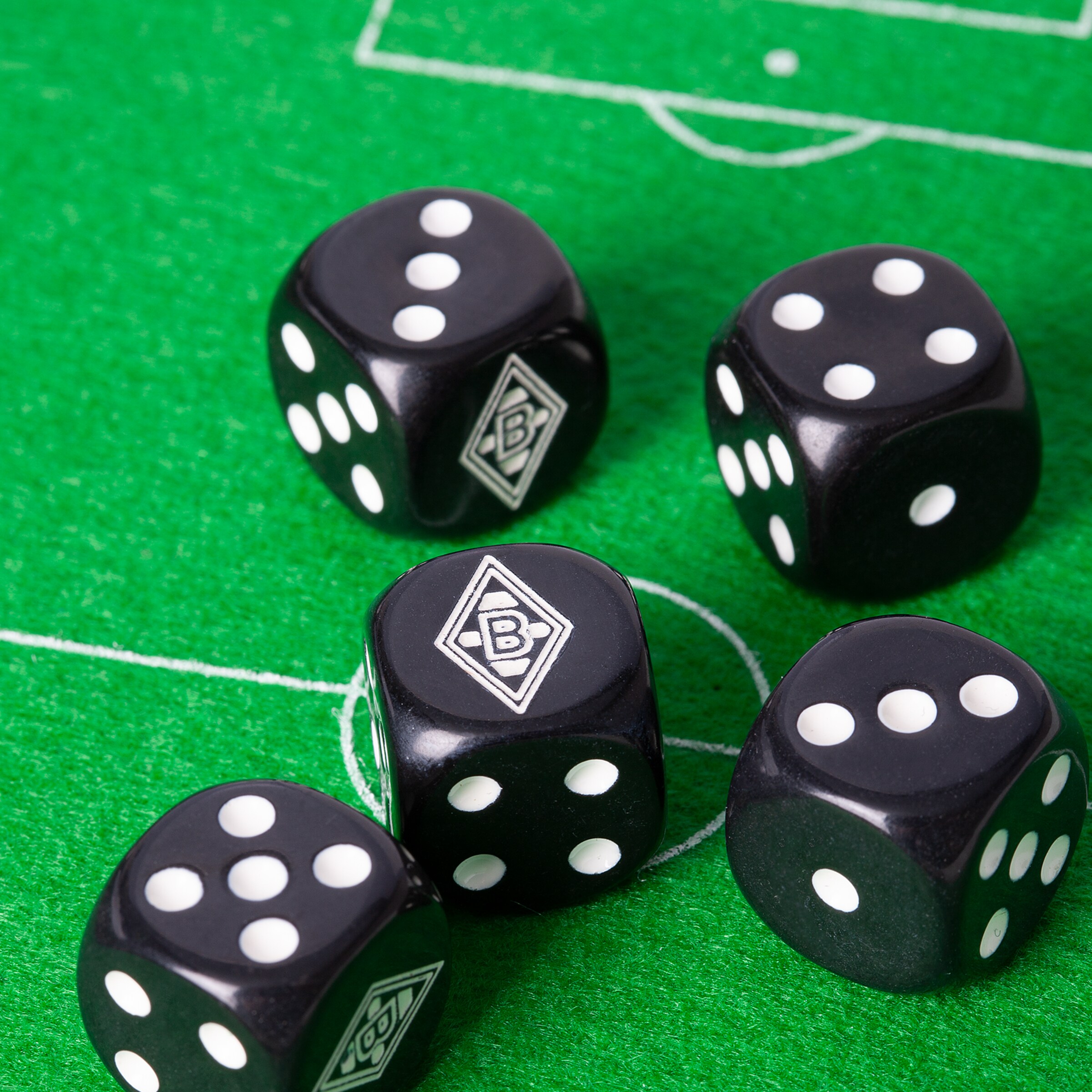 Five black dice with white dots and the Borussia Mönchengladbach logo on a green felt soccer field.