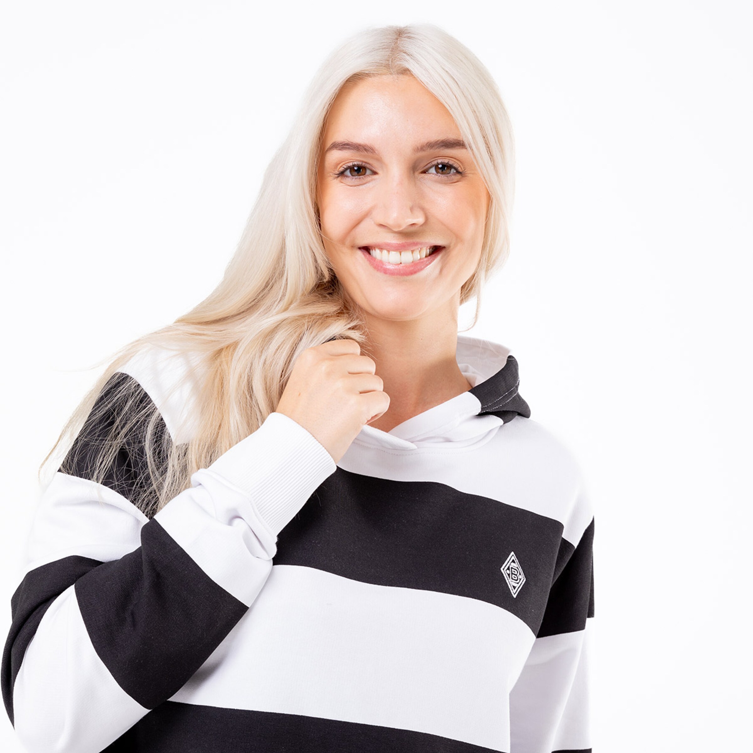 Junge Frau mit langen blonden Haaren in gestreifter Kapuzenjacke lächelt und schaut in die Kamera.