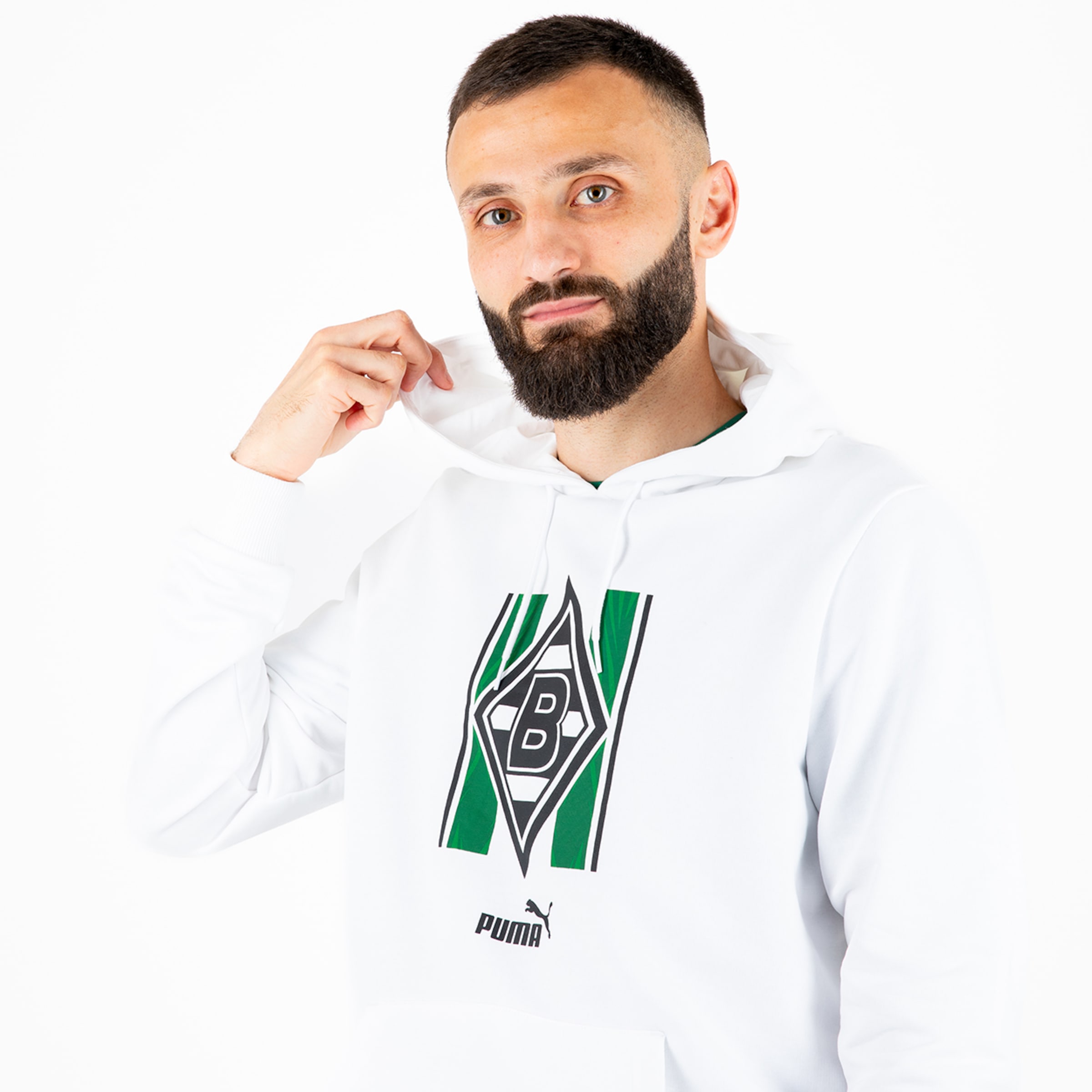 A man with a beard wearing a white hoodie featuring the Borussia Mönchengladbach logo.