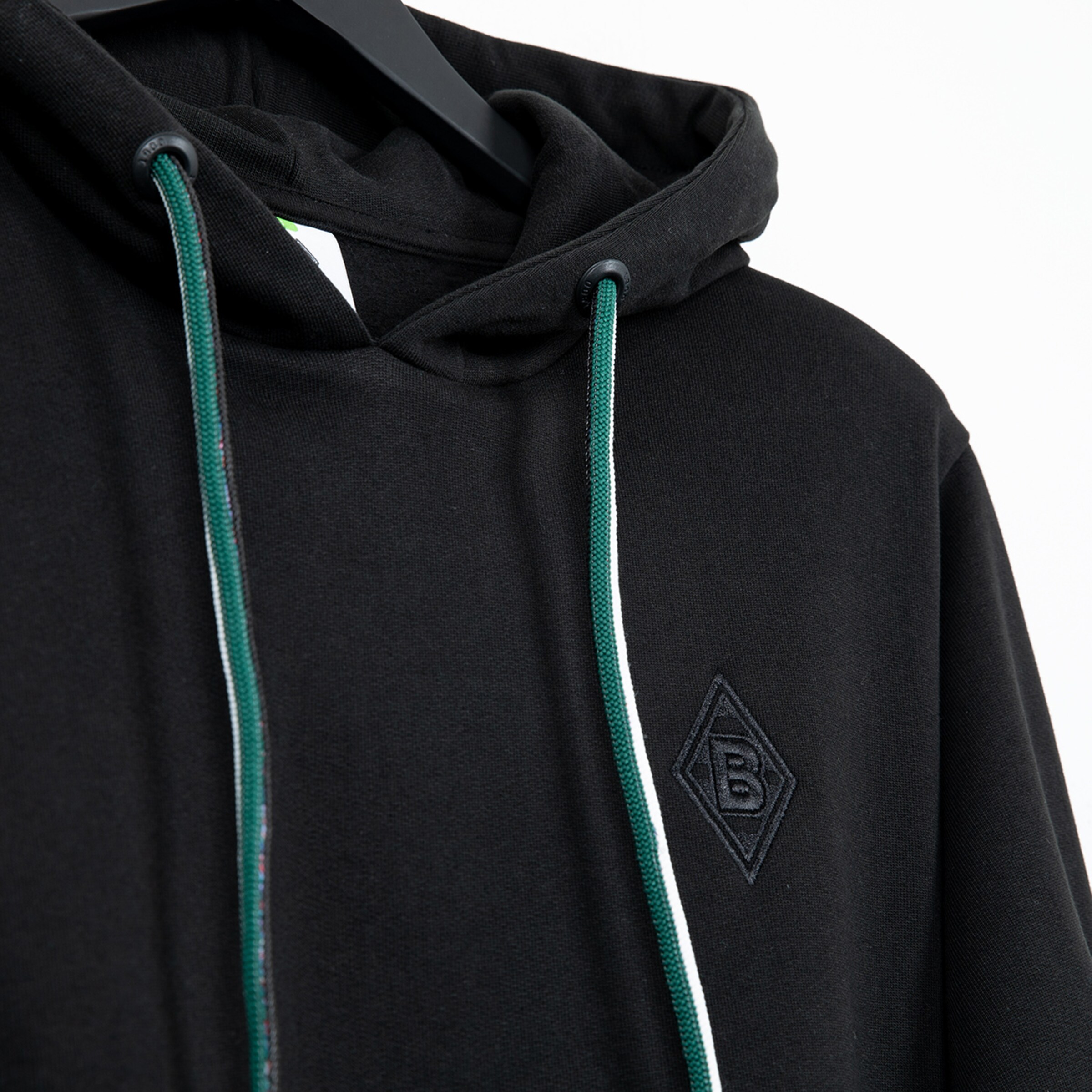 Schwarzer Hoodie mit grünen und weißen Kordeln markiert mit einem schwarzen Vereinslogo.