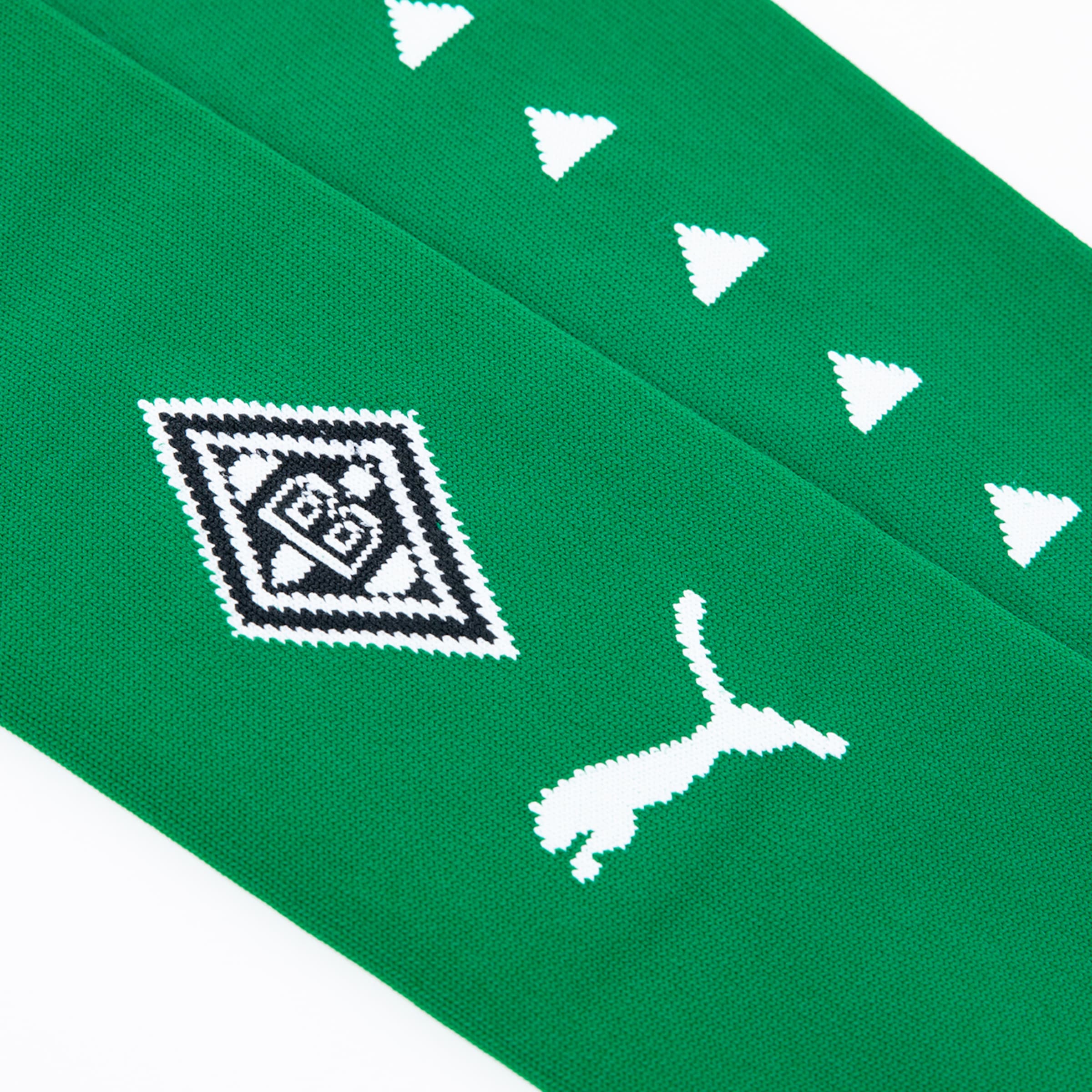 Nahaufnahme grüner Sportstutzen mit weißem Borussia Mönchengladbach-Wappen, Puma-Logo und einem Muster aus Dreiecken.