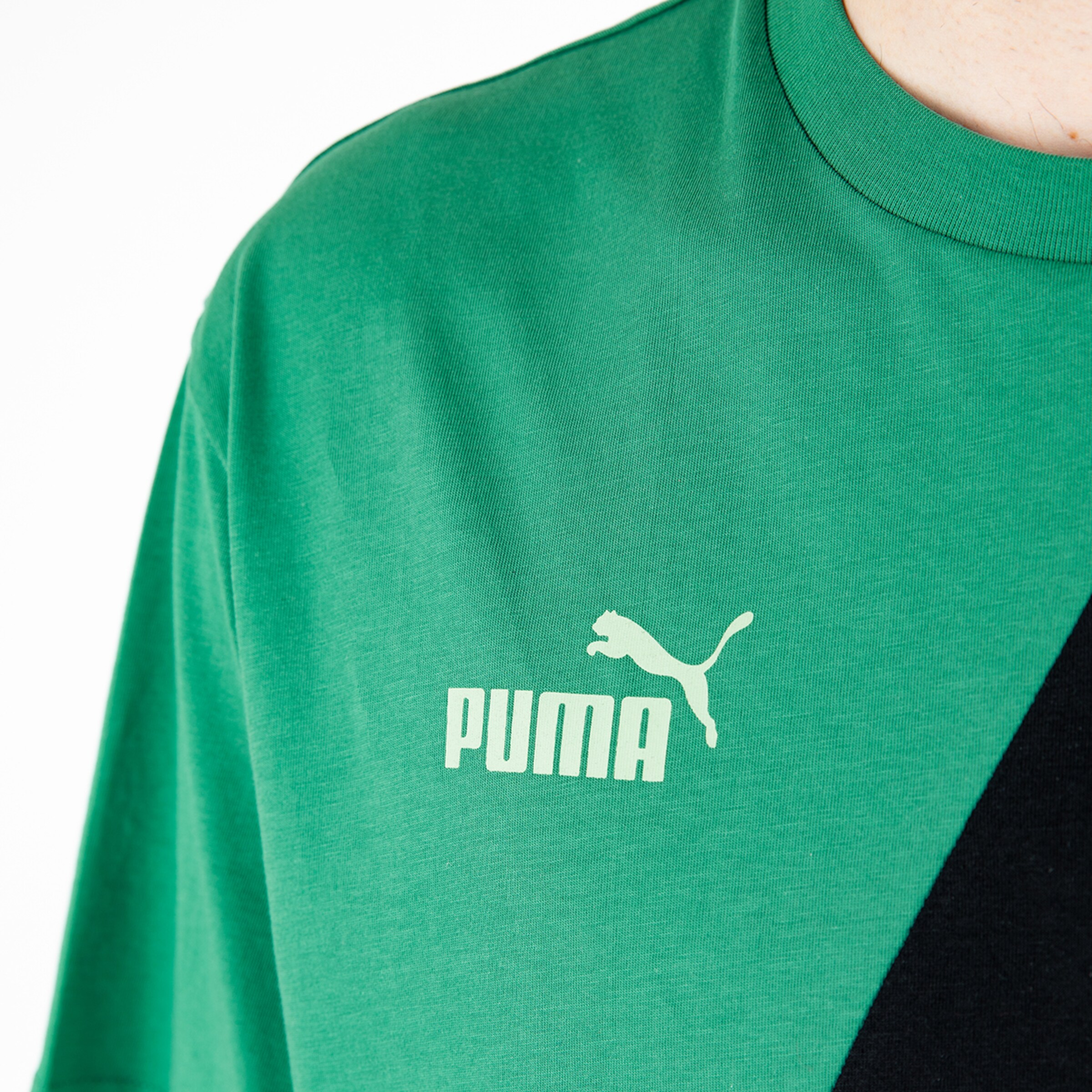 Ein grünes T-Shirt mit PUMA-Logo auf der linken Brust.