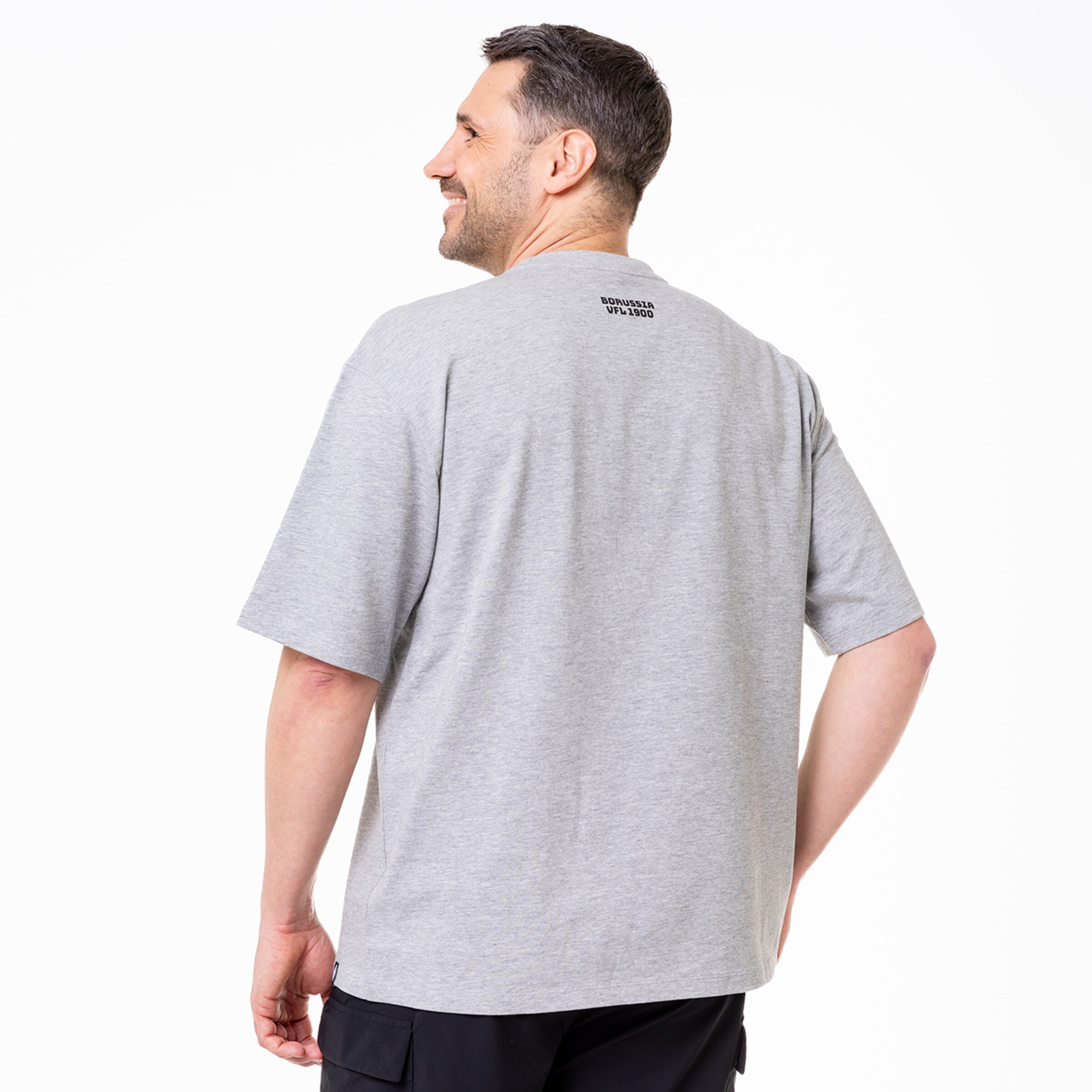 Mann mit lässigem grauem T-Shirt schaut über die Schulter.