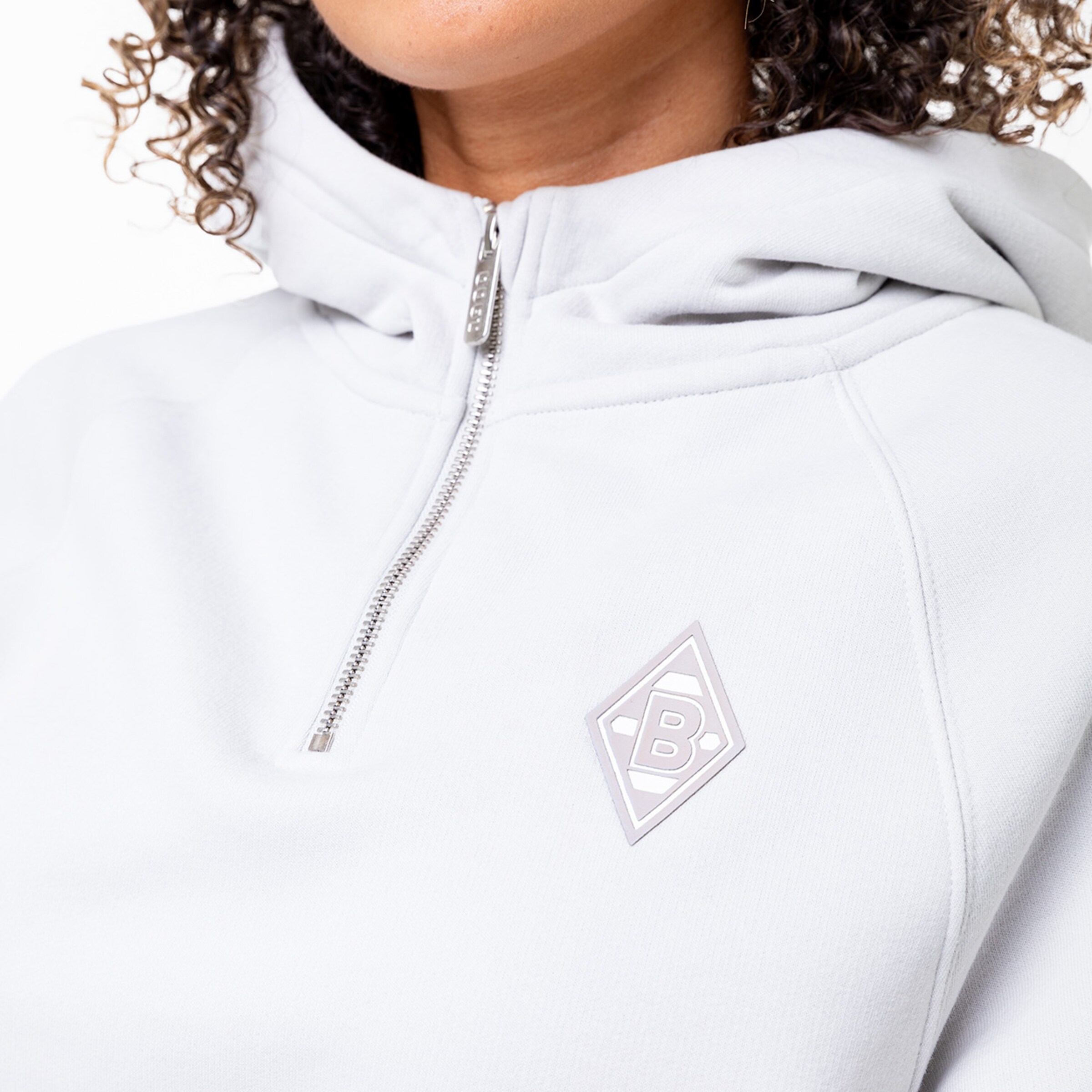 Nahaufnahme eines grauen Hoodies mit Zip und dem Borussia Mönchengladbach-Logo.