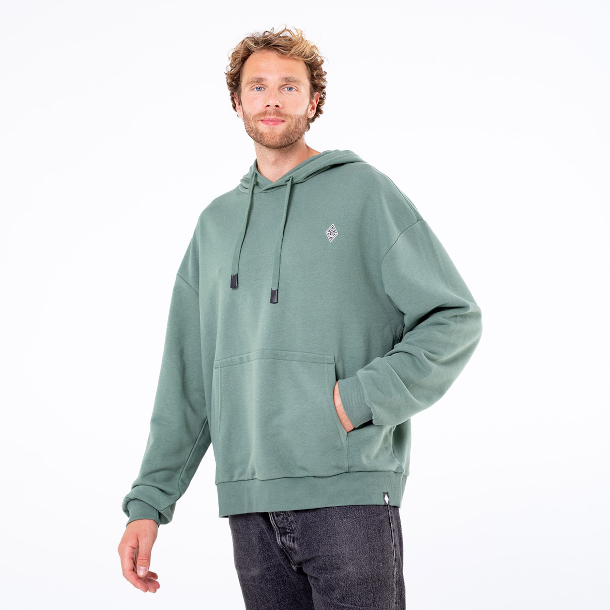 Mann in grünem Hoodie mit Kängurutasche und verstellbarer Kapuze lächelt frontal.