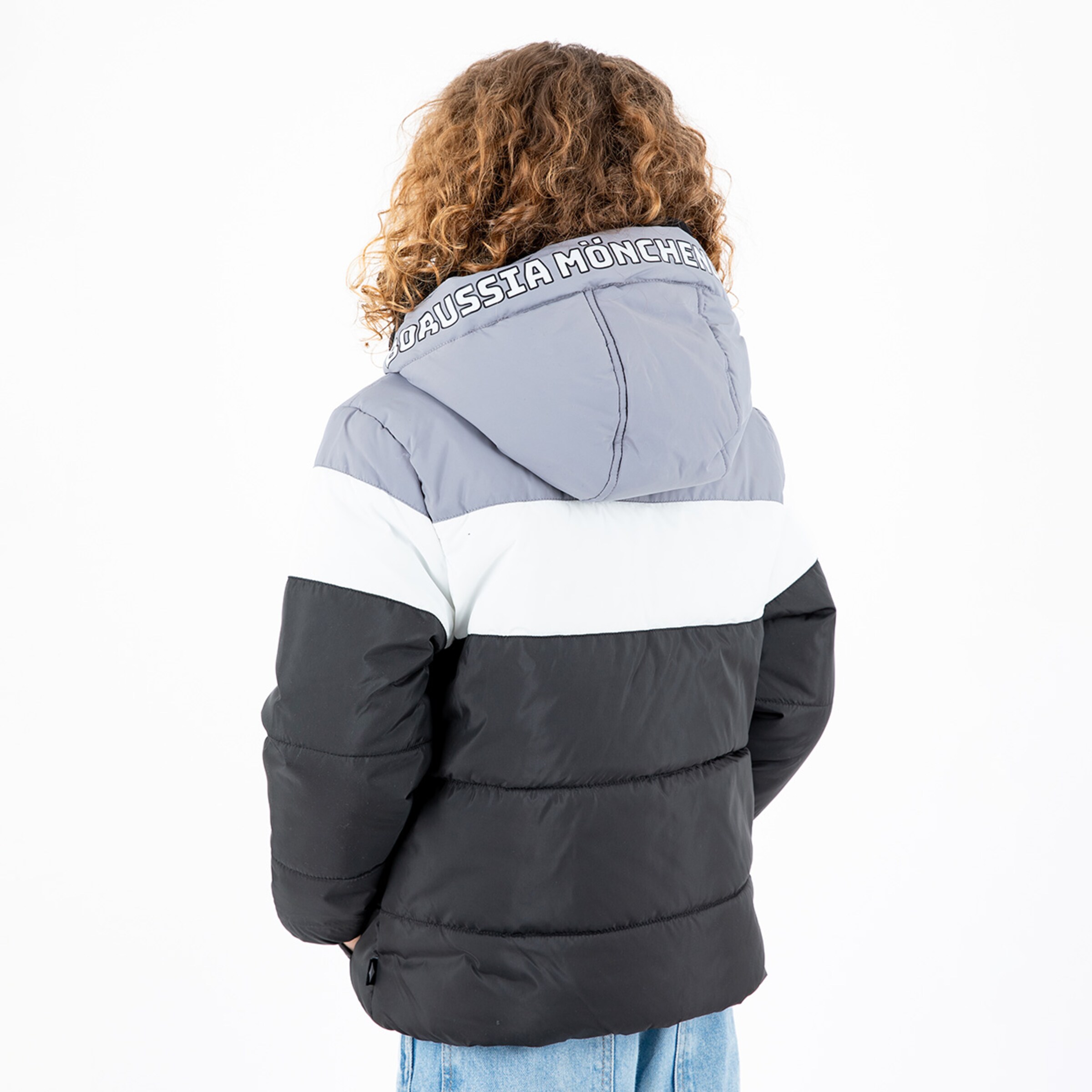 Boy with curly hair wearing a shiny multi-colored winter jacket featuring Borussia Mönchengladbach on the hood.