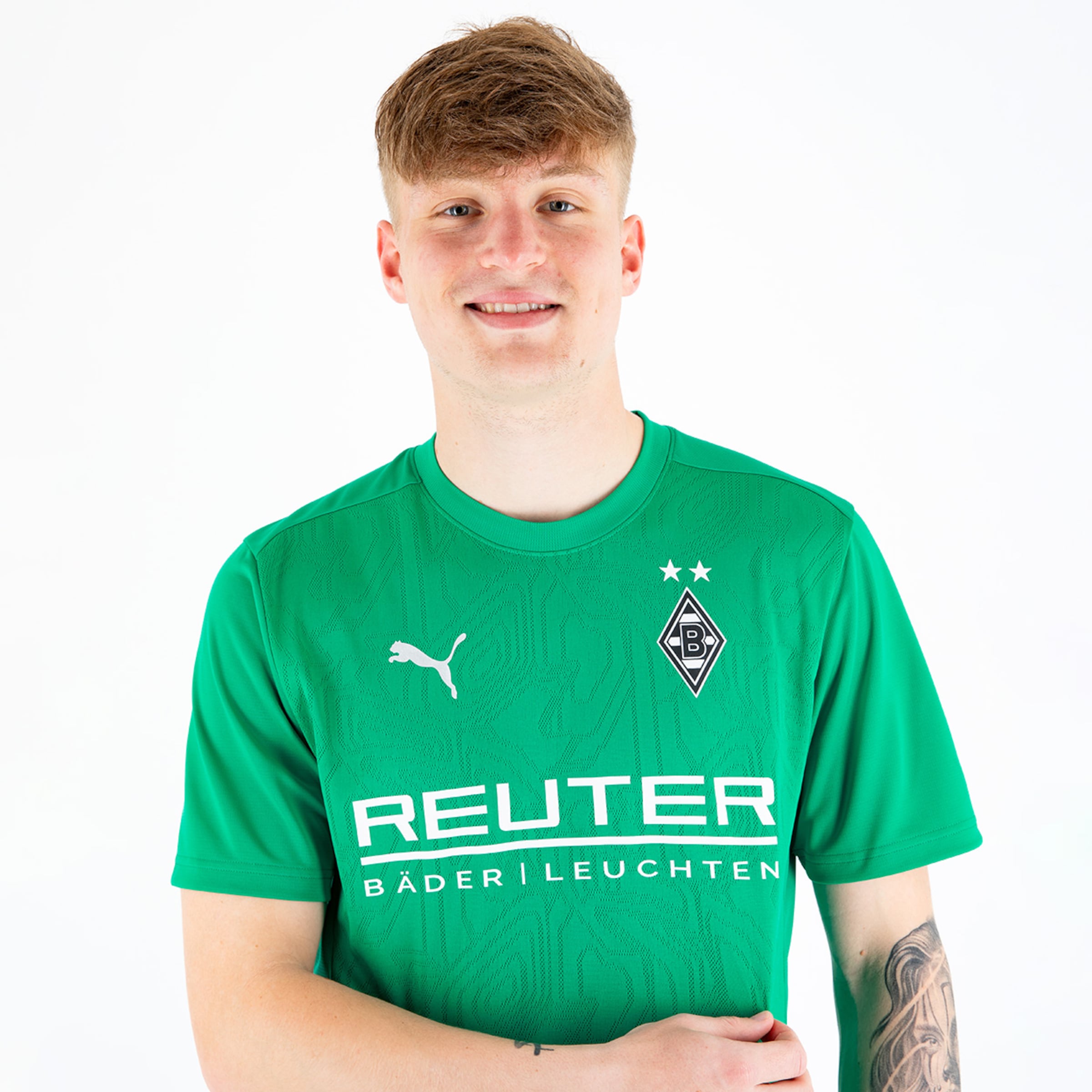 A young soccer player smiles in a green jersey featuring the Borussia Mönchengladbach logo.