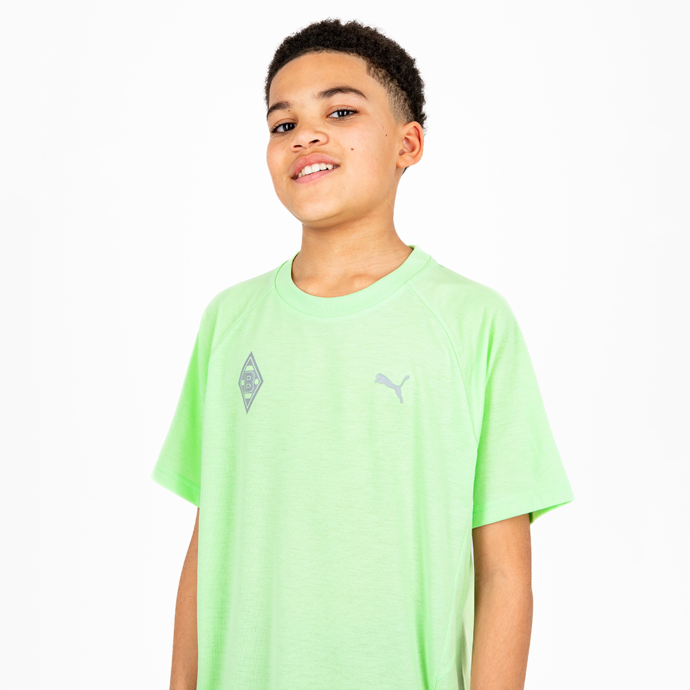 Kind trägt ein grünes T-Shirt mit Aufdruck des Vereinswappens von Borussia Mönchengladbach und dem Puma-Logo.