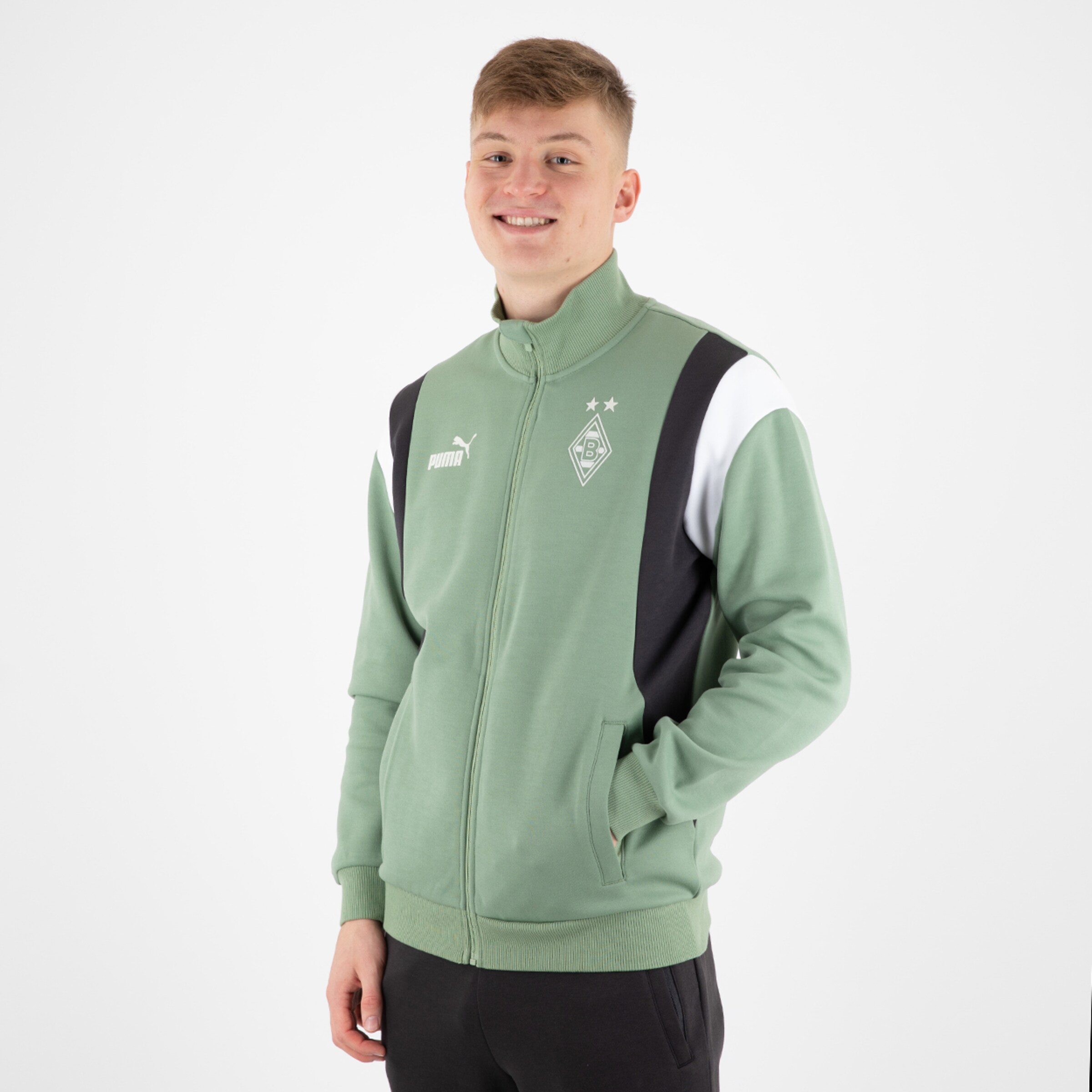 Ein junger Mann in einer grünen Trainingsjacke mit dem Borussia Mönchengladbach-Logo.