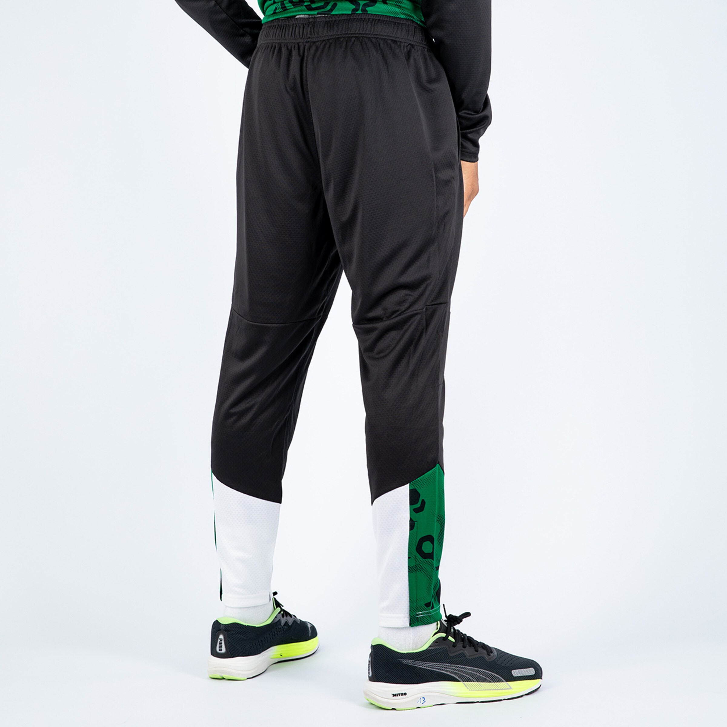 Schwarze Trainingshose mit grünen und weißen Details Rückansicht.
