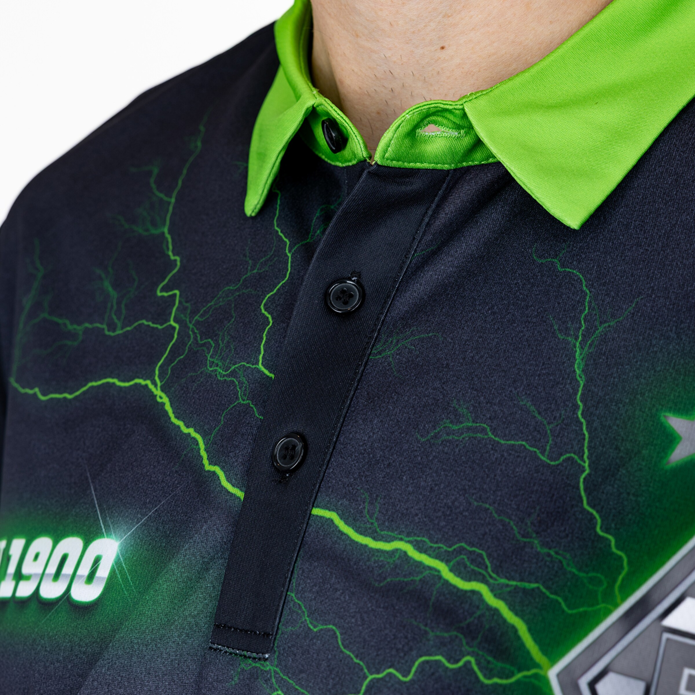 Nahaufnahme eines schwarzen Poloshirts mit neongrünem Kragen, grünem Blitzmuster und der Zahl 1900.