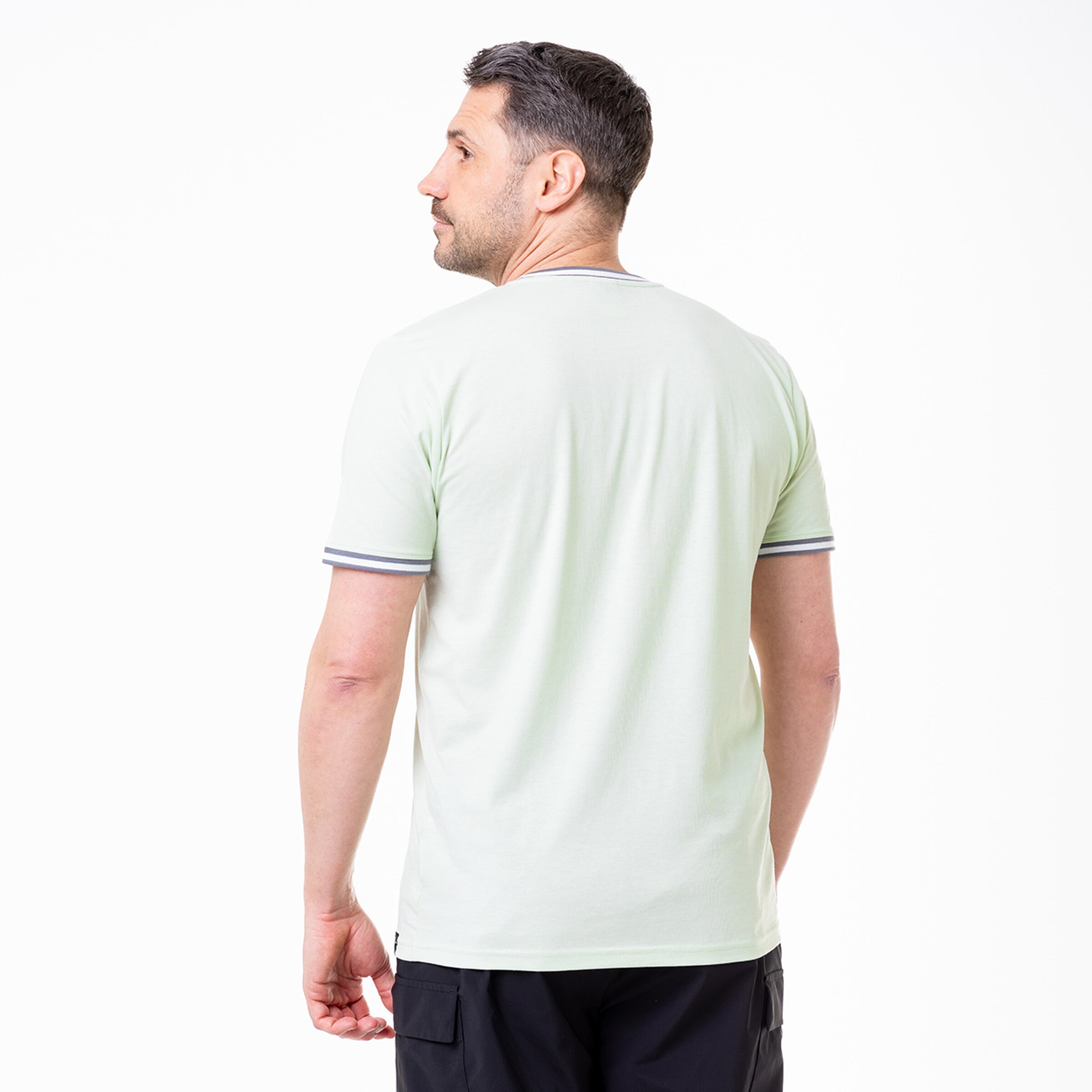 Man in black shorts and green T-shirt viewed from behind featuring contrast stripes.