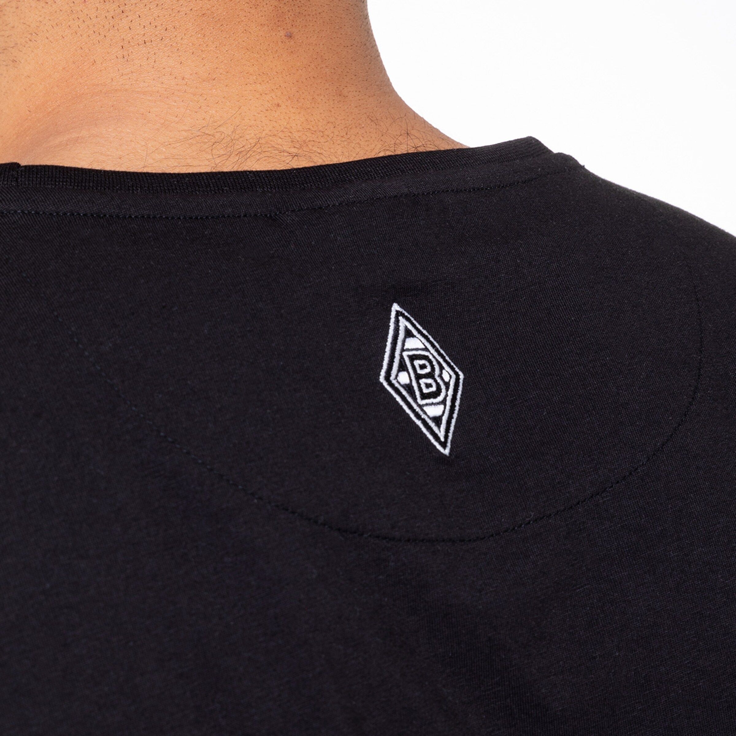 Detailaufnahme des Rückens eines T-Shirts mit gesticktem Borussia Mönchengladbach Logo.