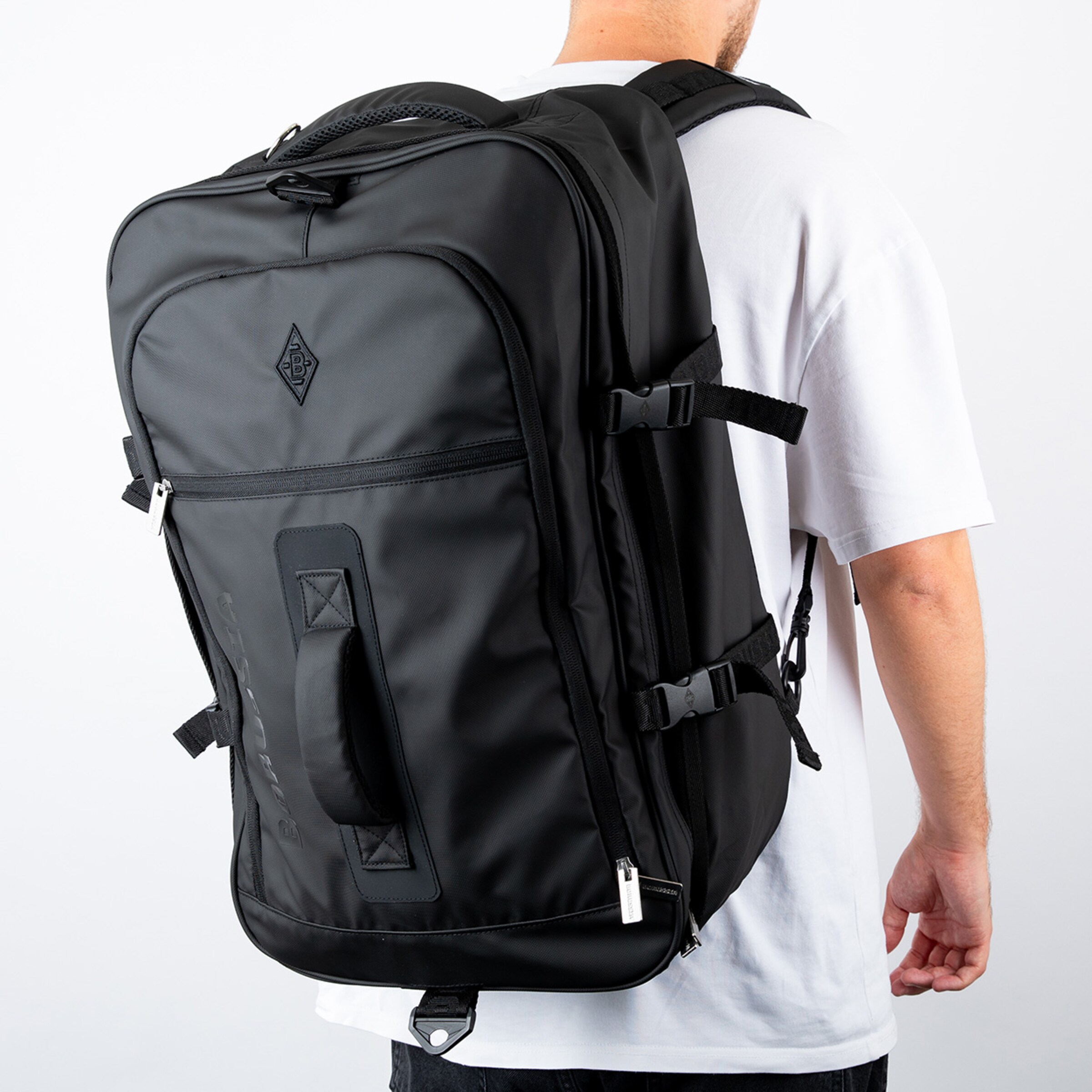 Schwarzer Rucksack auf dem Rücken eines Mannes der ein weißes T-Shirt trägt.